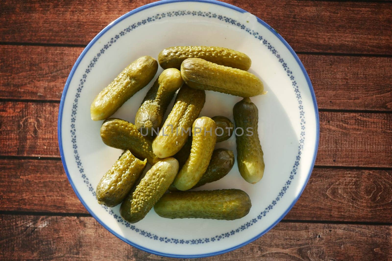A bowl of freshly prepared pickles sits on a rustic wooden table.