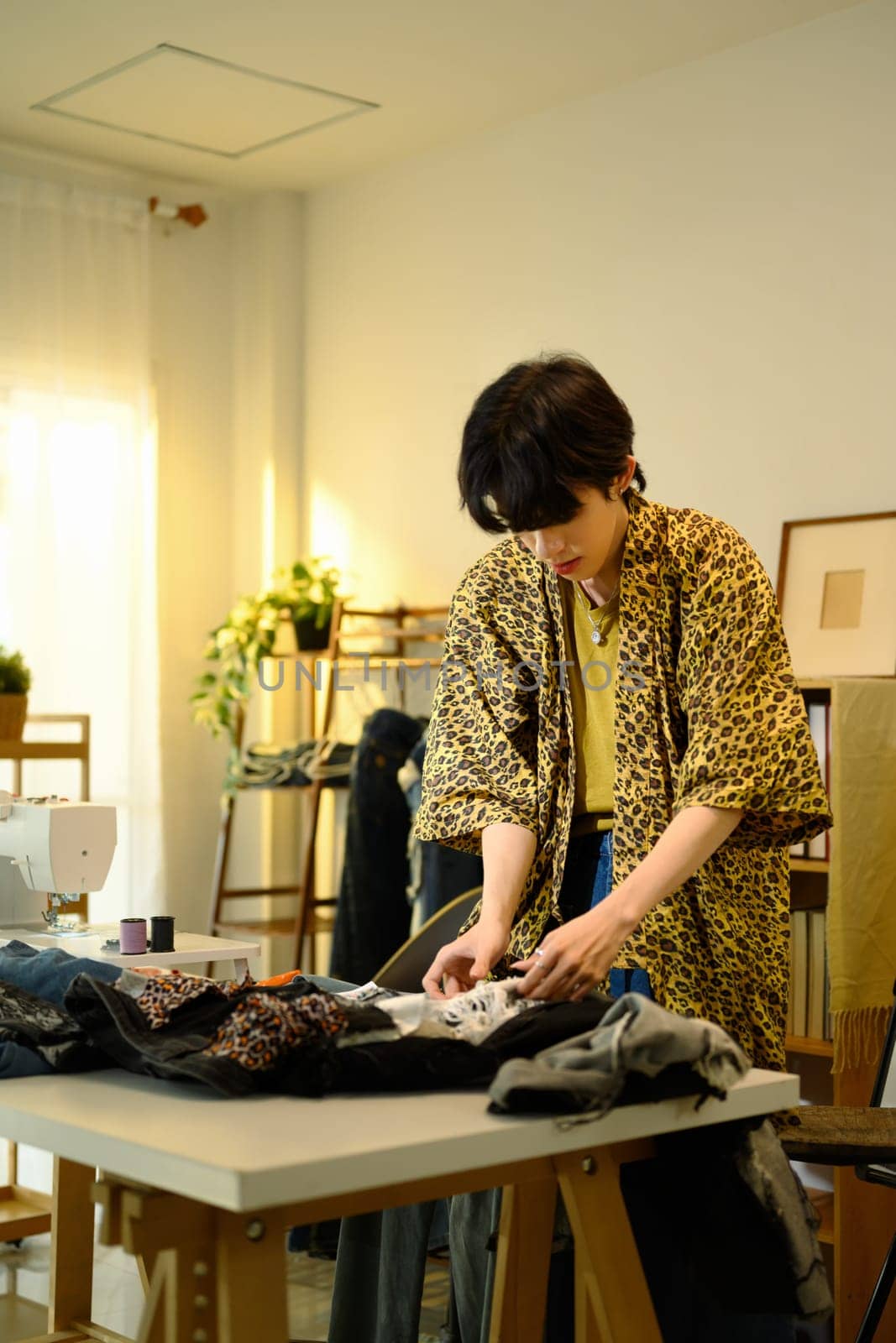 Young fashion designer customizing jeans in a creative studio.