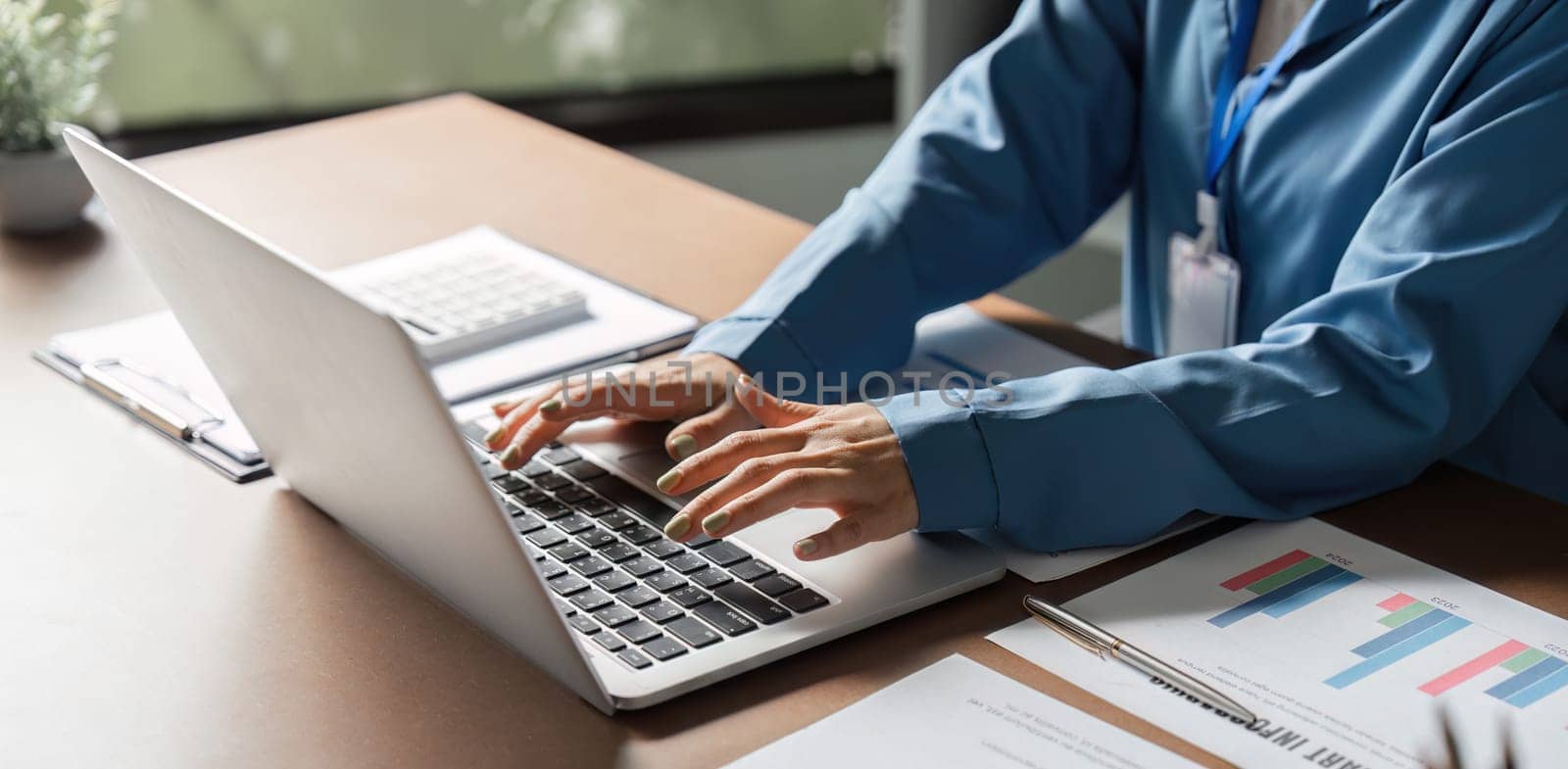 A business professional using a laptop to analyze reports and manage finances in a modern office environment.