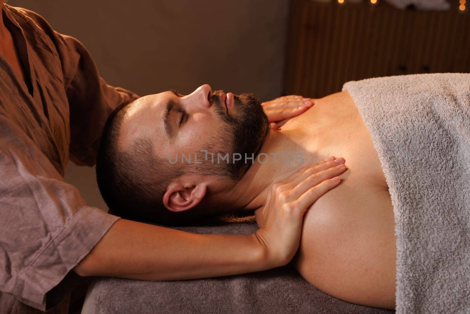 Man enjoying a soothing shoulder and neck massage in a tranquil spa, surrounded by soft lighting and a relaxing ambiance.