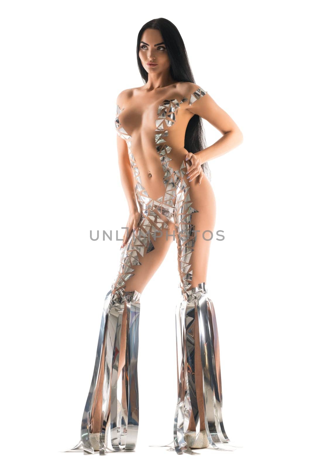 Curvy female with naked body covered with creative foil pieces standing on white background in studio