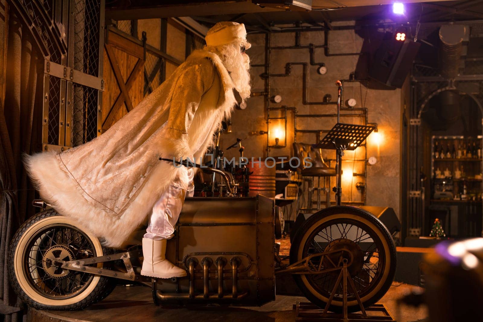 Side view of brutal Santa Claus in white clothes standing on vintage motorbike in grunge rock bar
