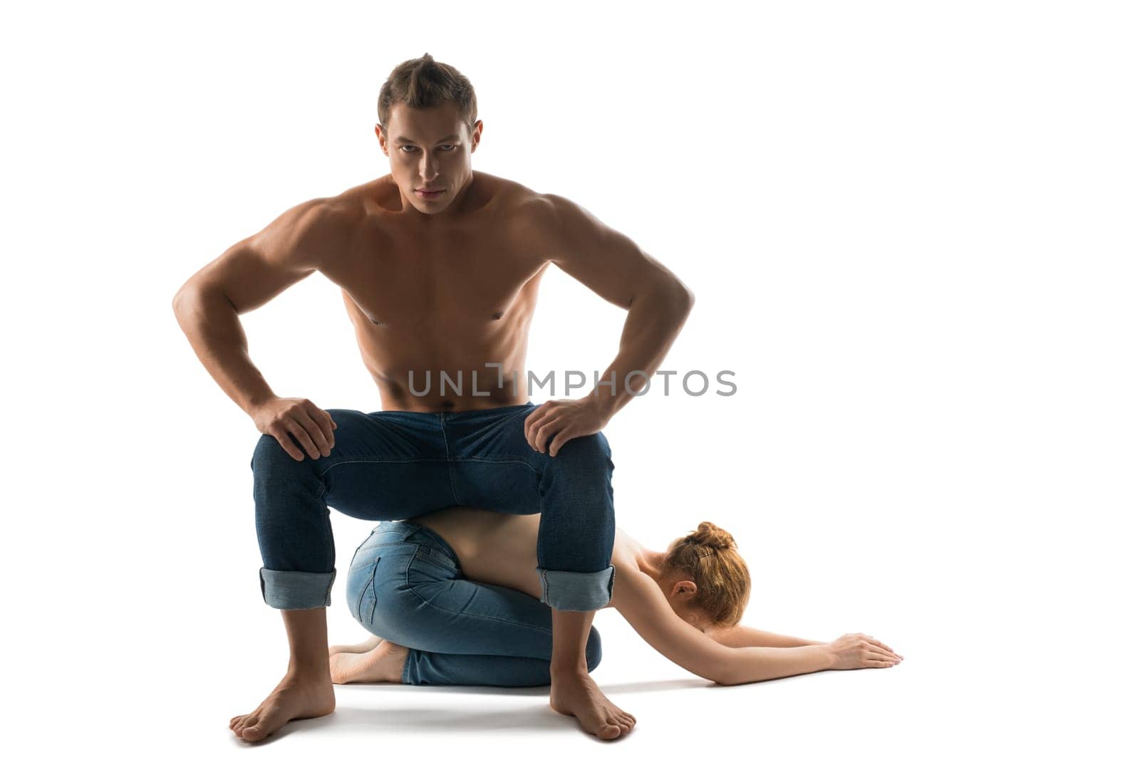 Shirtless male with strong body sitting on back of slender topless female while demonstrating concept of abusive relationship