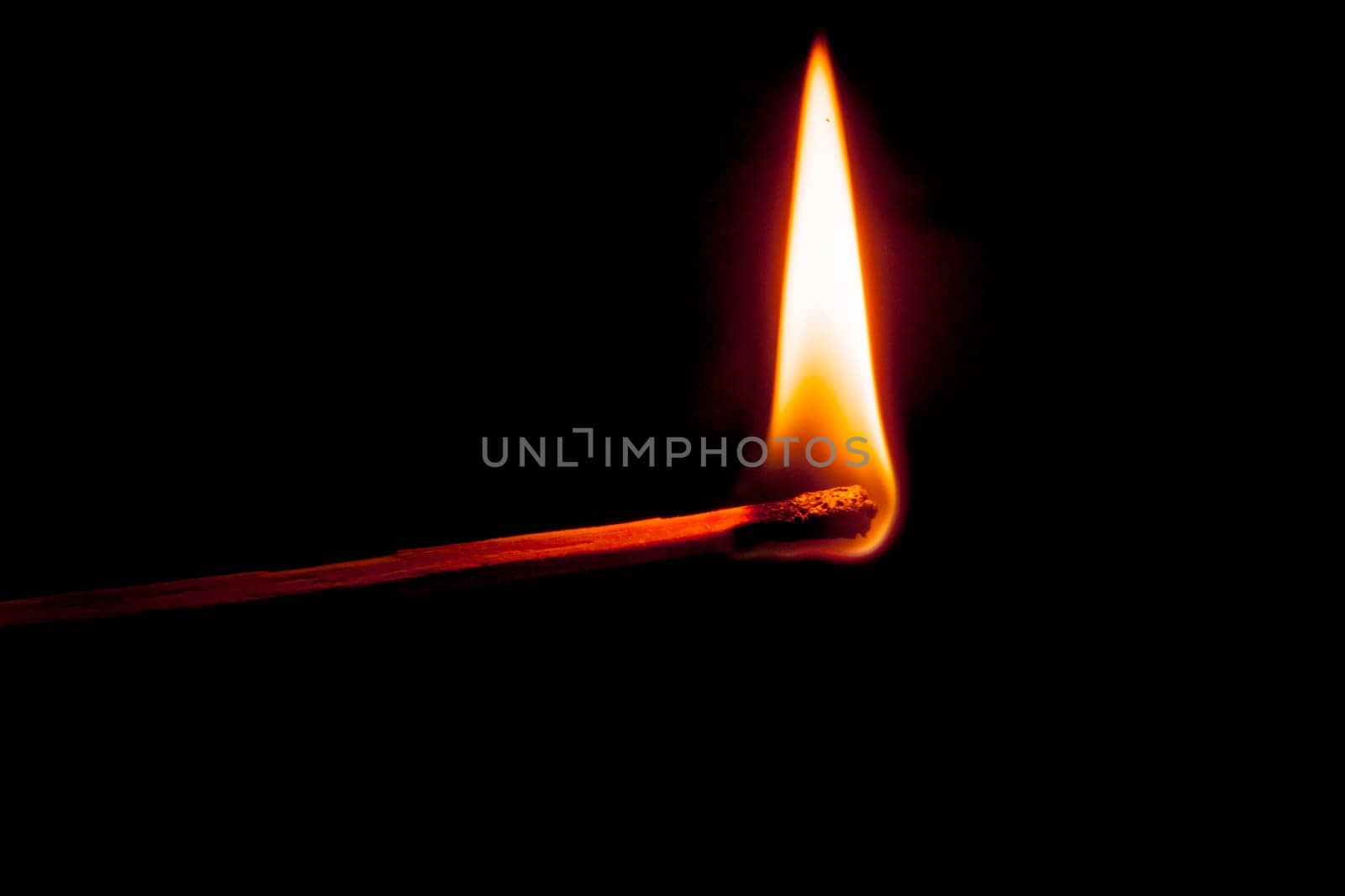 Side view of a burning match isolated on black.