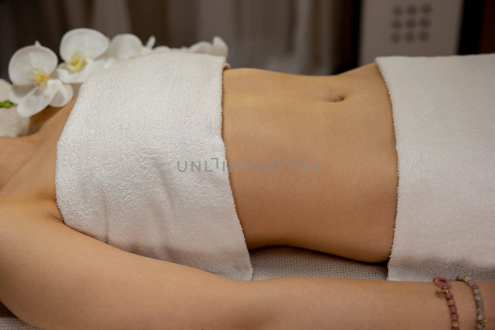 A serene spa scene features a relaxed person in towels, surrounded by orchids, evoking calm and tranquility