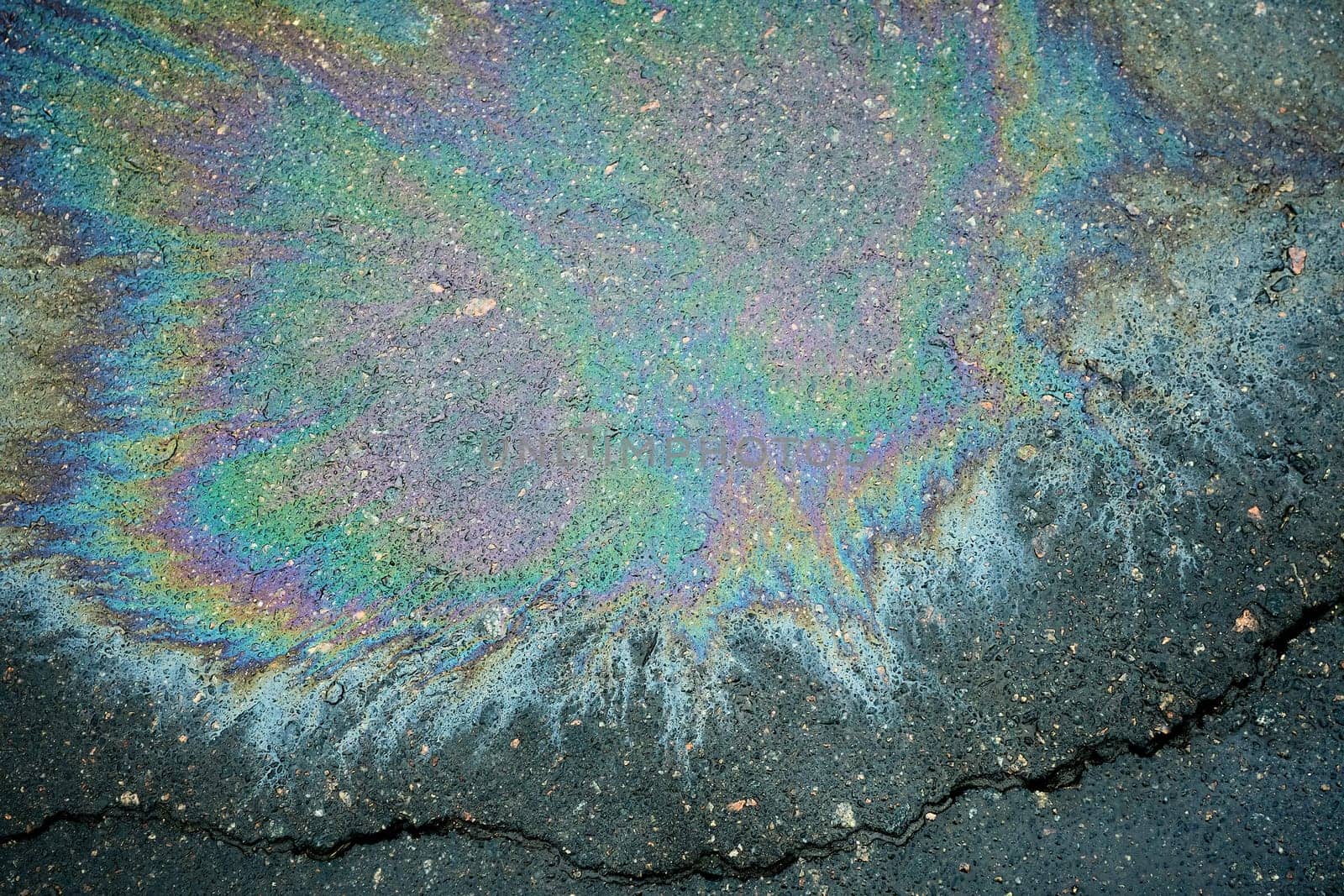 Cracked pavement with vibrant oil spill patterns.