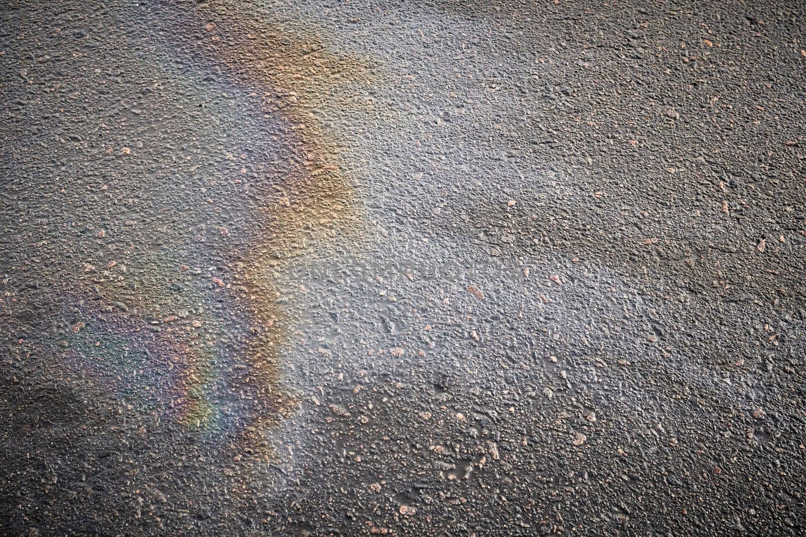 Detailed view of oil stains on the road surface, showcasing the vibrant colors of gasoline as a captivating texture