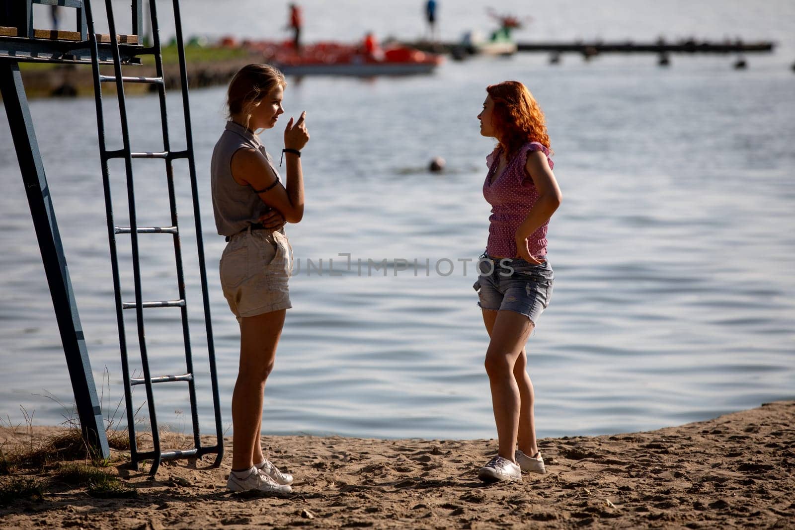 On a beautiful sunny day at the beach, two women are happily engaged in a lively conversation amidst gorgeous scenery