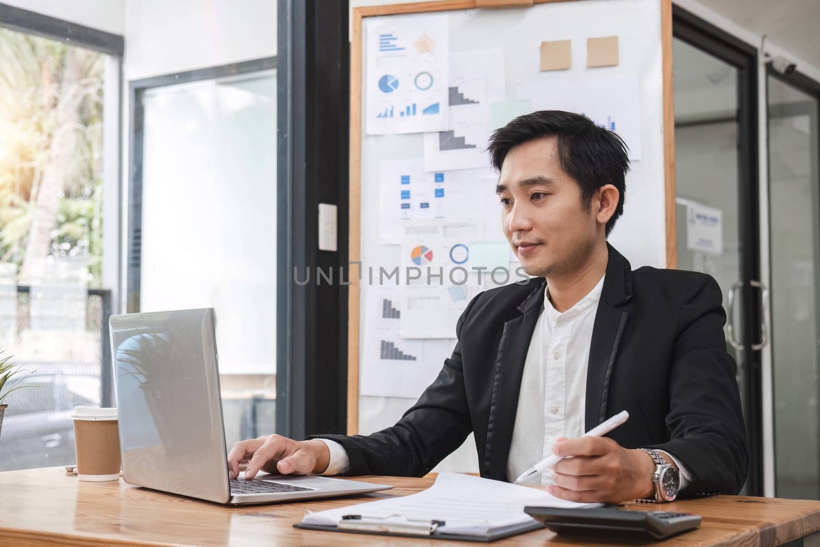 Young Asian businessman working on laptop in office.