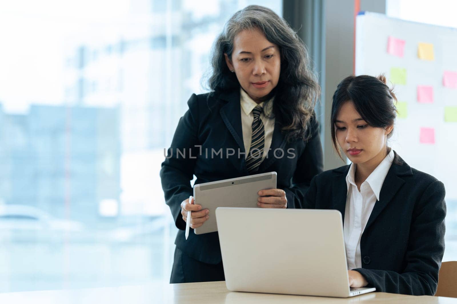 Two diverse financial assistant working on laptop while senior professional standing and giving investment advise by itchaznong