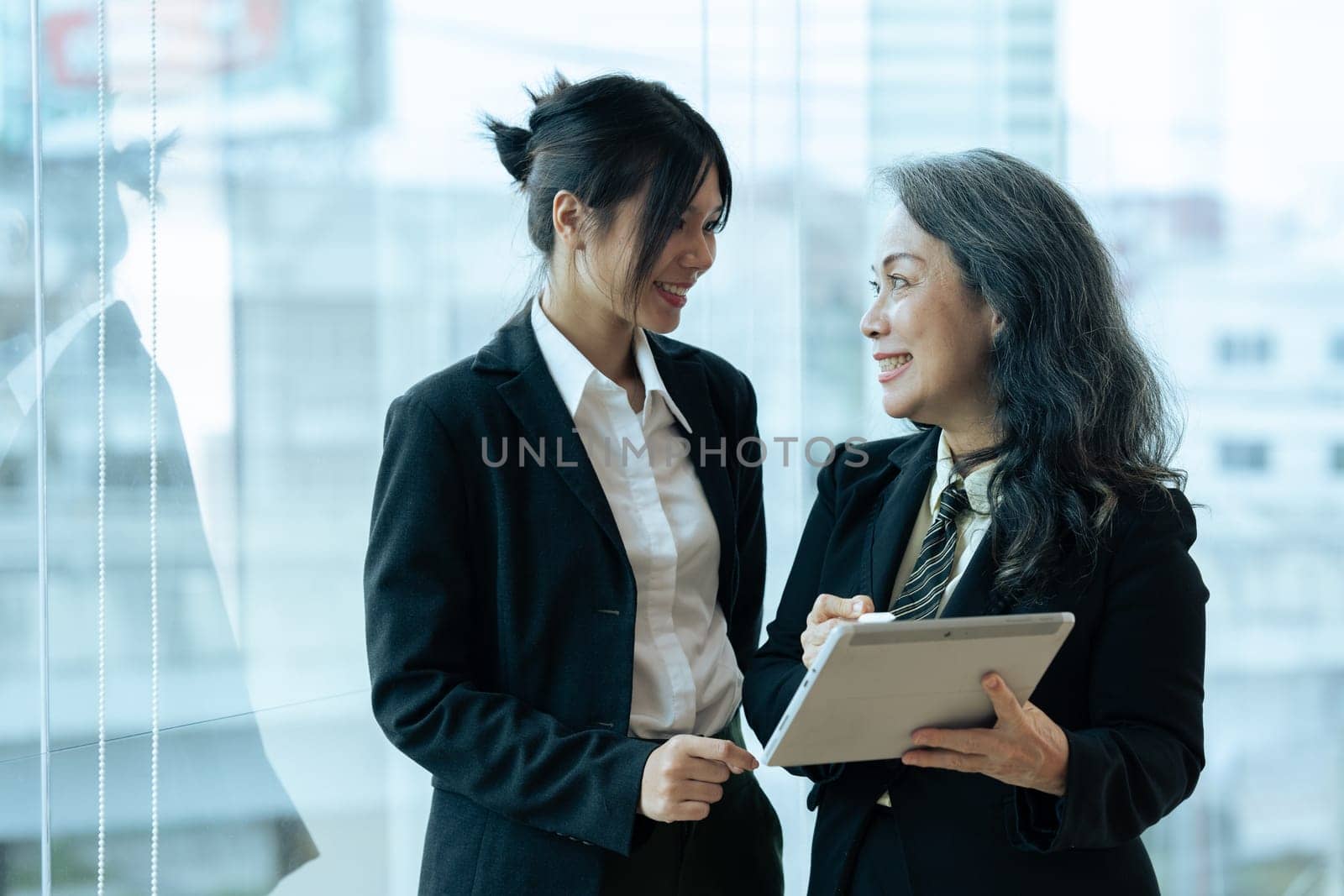 Two happy diverse coworker discussing report financial on tablet, working on project together by itchaznong