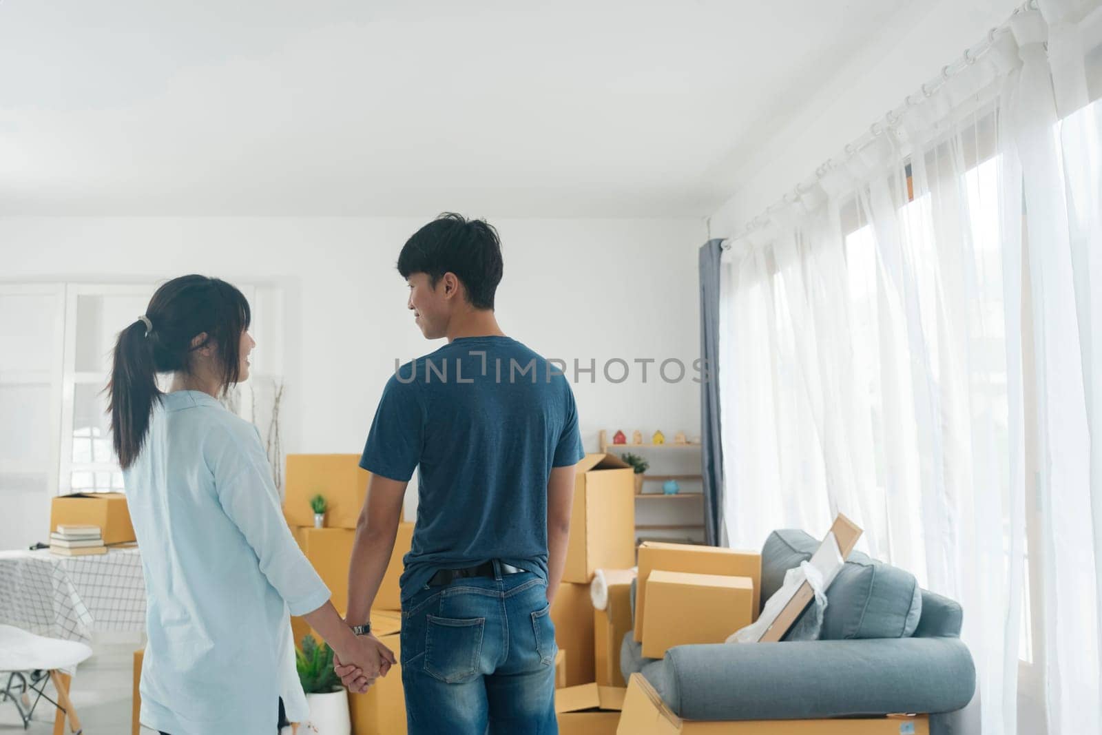 Asian young happy new married couple moving to their new house or real estate. An attractive romantic man and woman carry boxes parcel with happiness and love. Family moving house relocation concept.