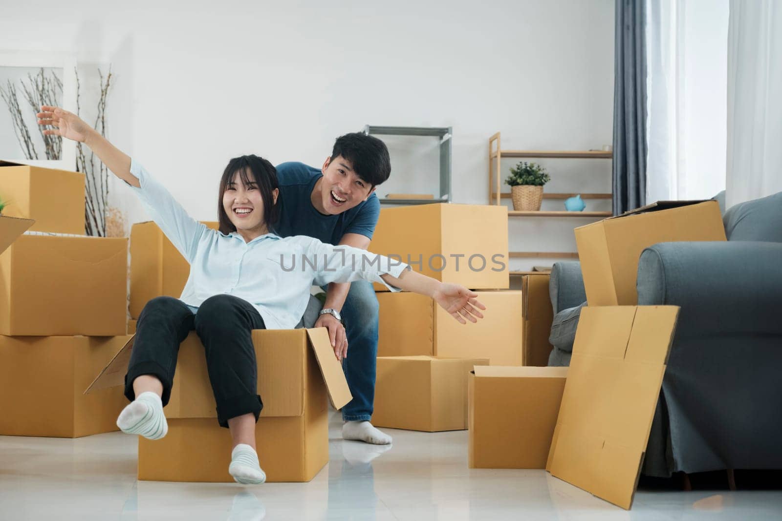 Happy couple is having fun with cardboard boxes in new house at moving day.