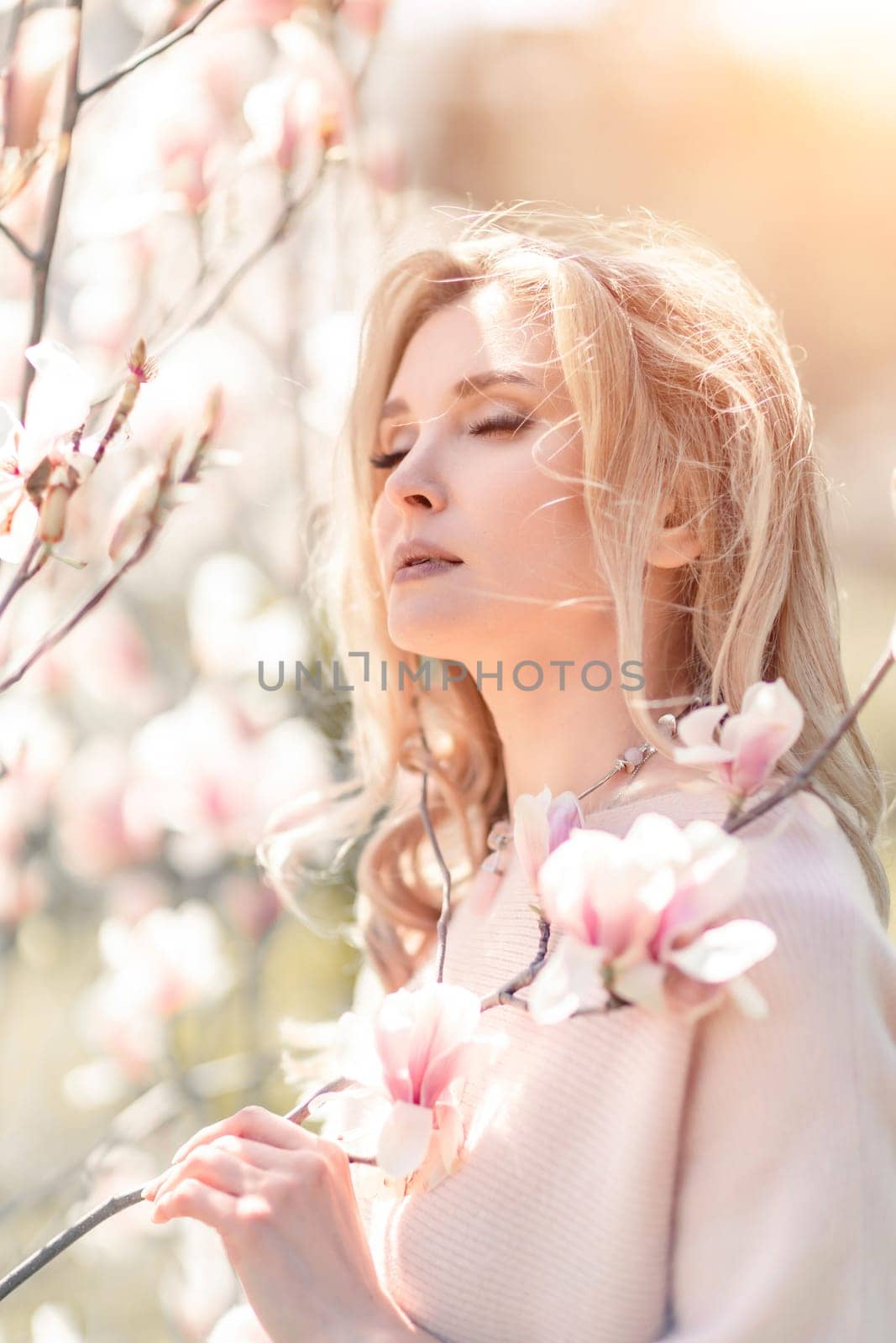 Magnolia woman portrait. Happy middle aged woman enjoying the smell in a blooming spring garden. Beautiful magnolia bushes, large flowers. by Matiunina