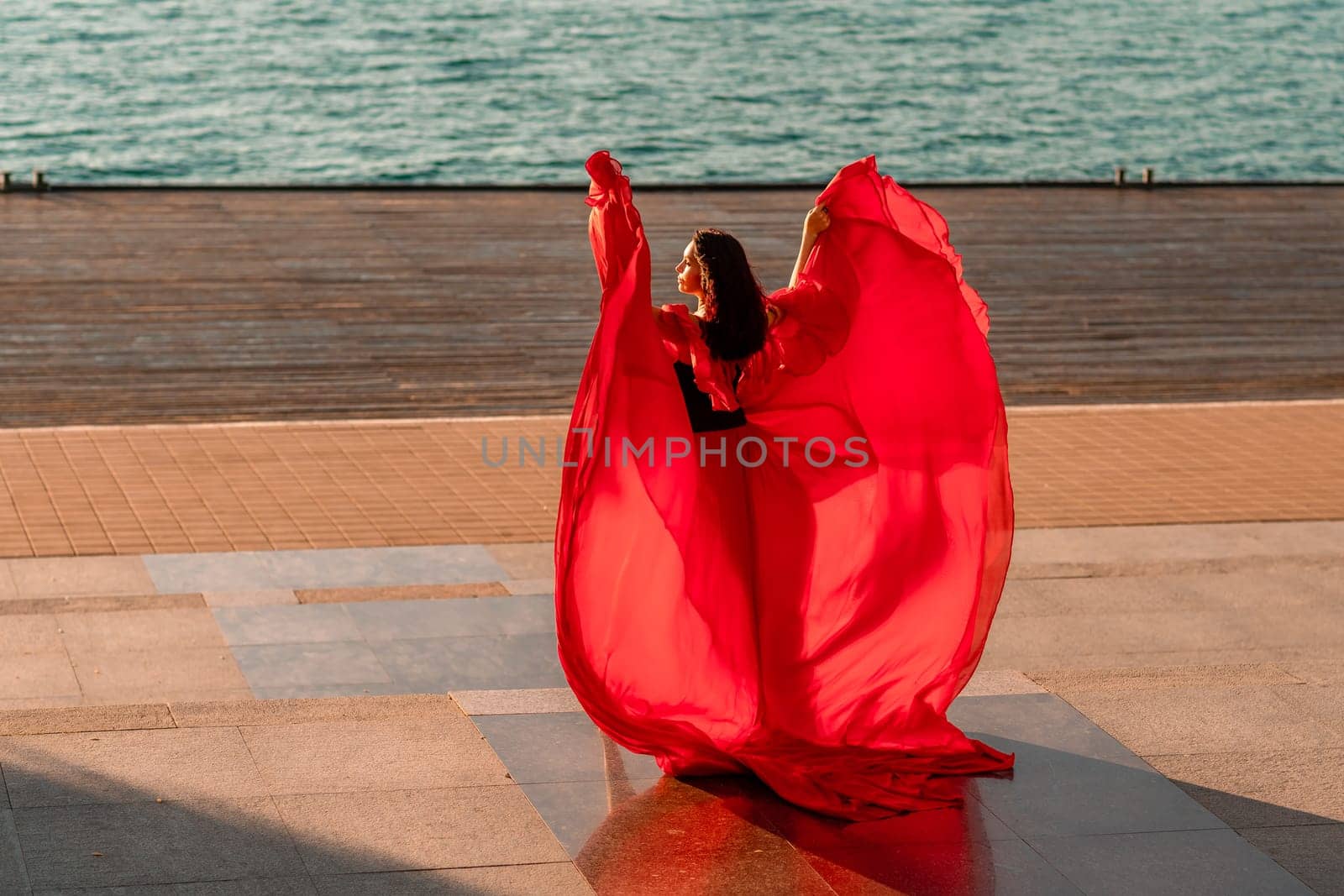 Sunrise red dress. A woman in a long red dress against the backdrop of sunrise, bright golden light of the sun's rays. The concept of femininity, harmony. by Matiunina