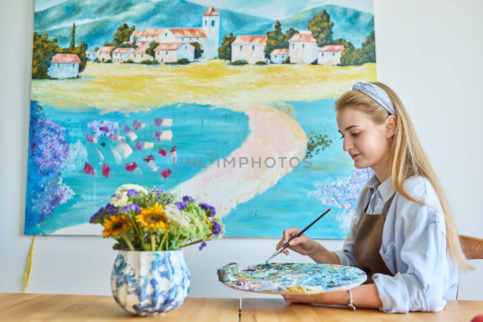 Young woman artist painting picture on canvas on wall by VH-studio