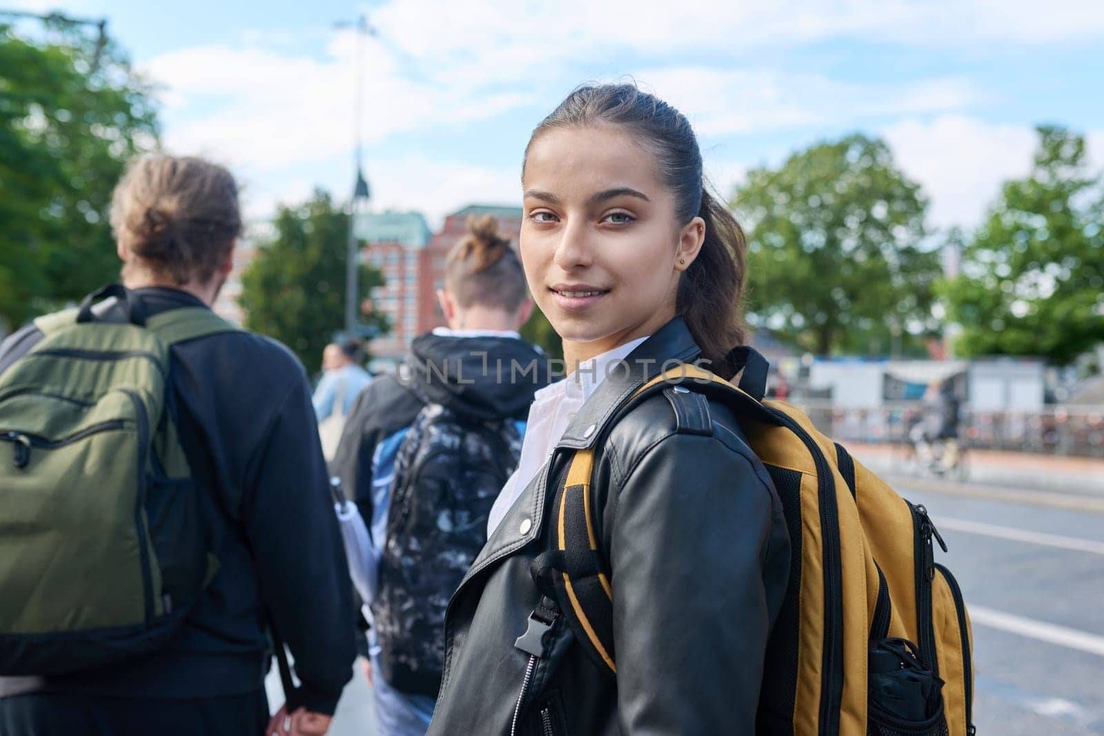 Portrait of teenage high school student, smiling confident girl 16, 17 years old with backpack looking at camera outdoor, on street of modern city. Urban life, adolescence, education, youth concept