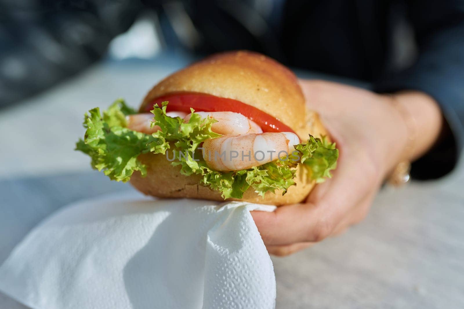 Traditional street sea food, shrimp burger, close-up in outdoor hands.
