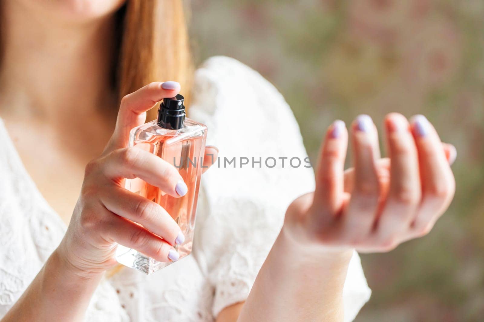 Beautiful young woman using perfume at home.