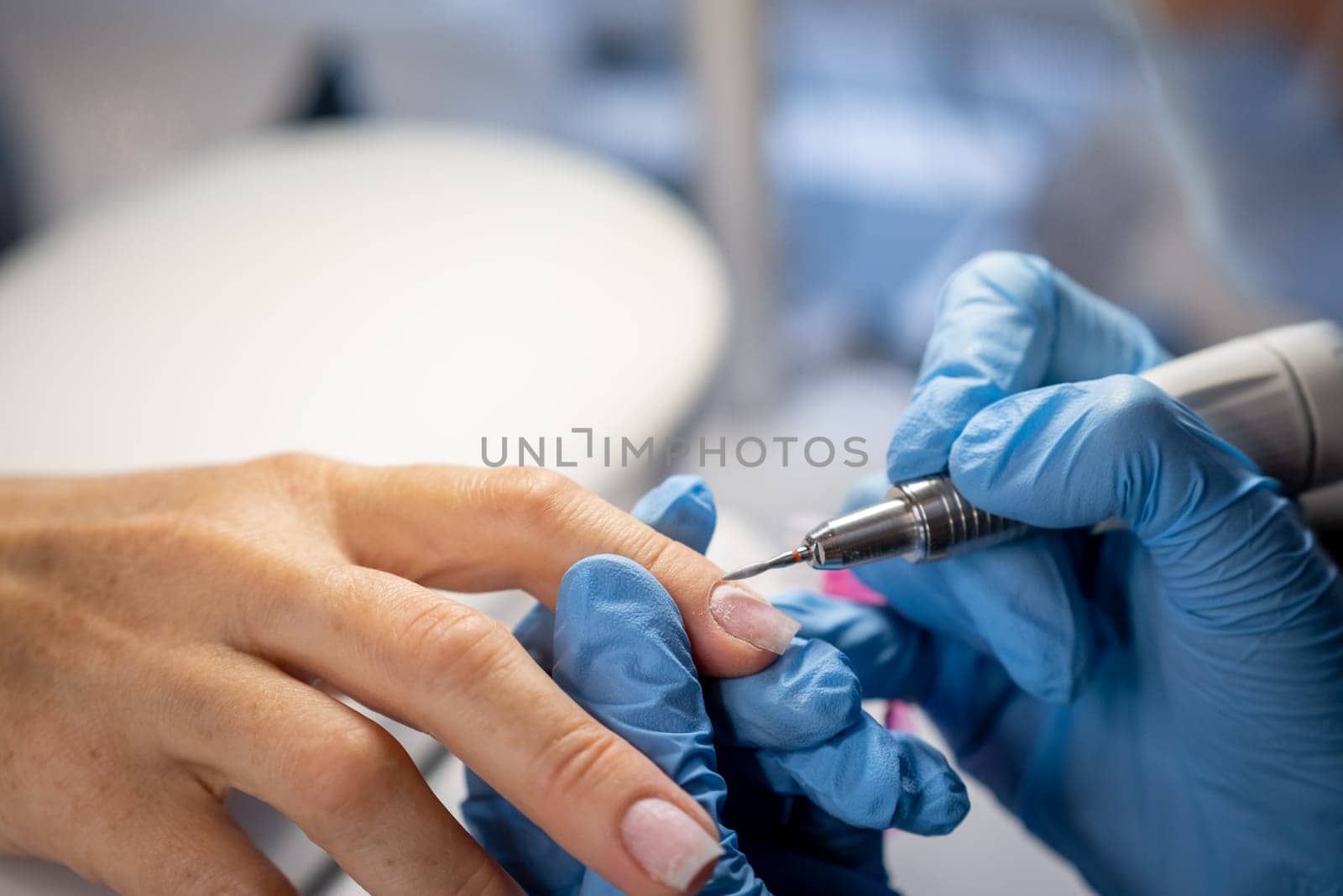 Nail care procedure in a beauty salon. Female hands and tools for manicure, process of performing manicure in beauty salon. Concept spa body care. Gloved hands of a skilled manicurist cutting cuticles