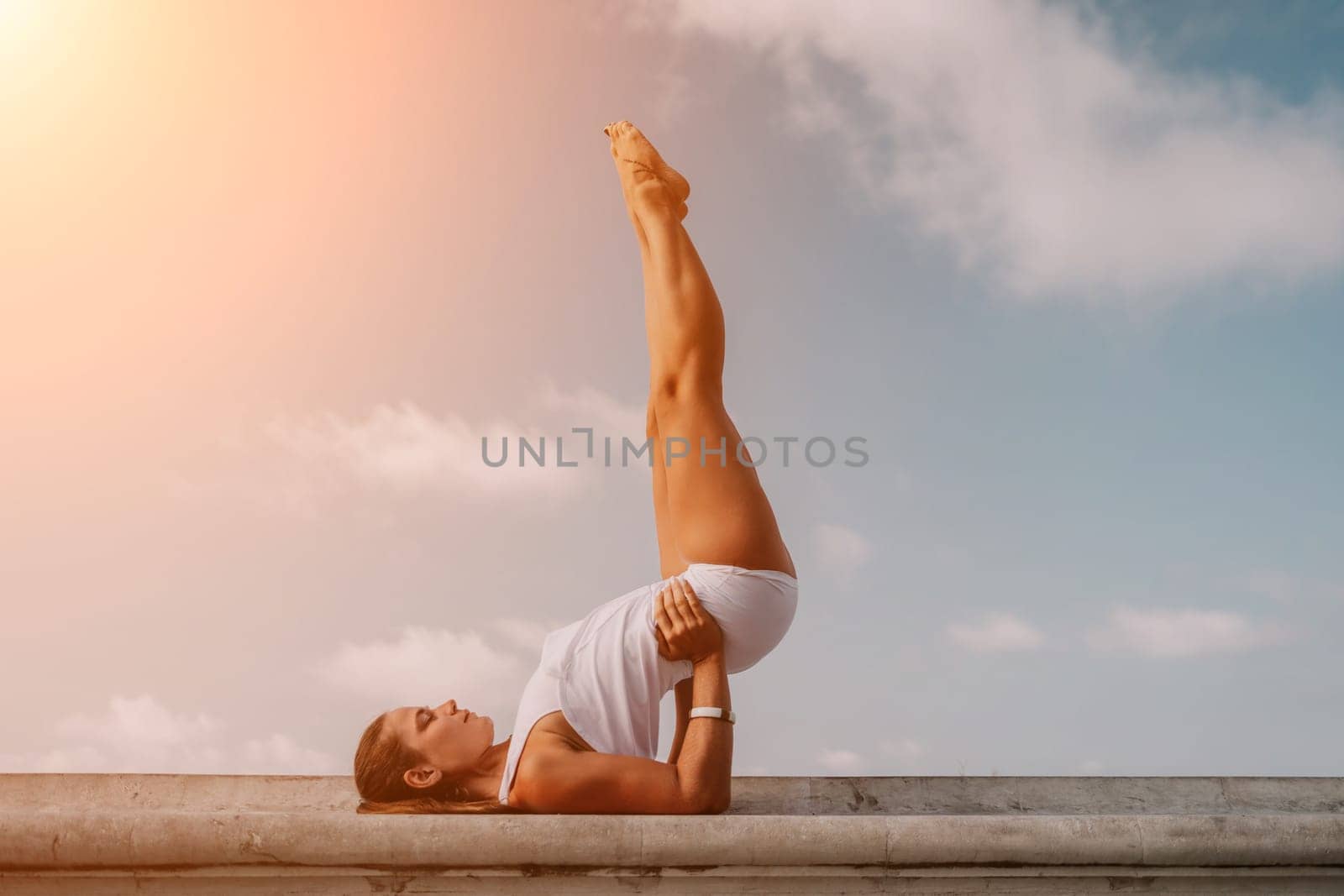 Fitness woman sea. A happy middle aged woman in white sportswear exercises morning outdoors in a park with a beach view. Female fitness pilates yoga routine concept. Healthy lifestyle. by panophotograph