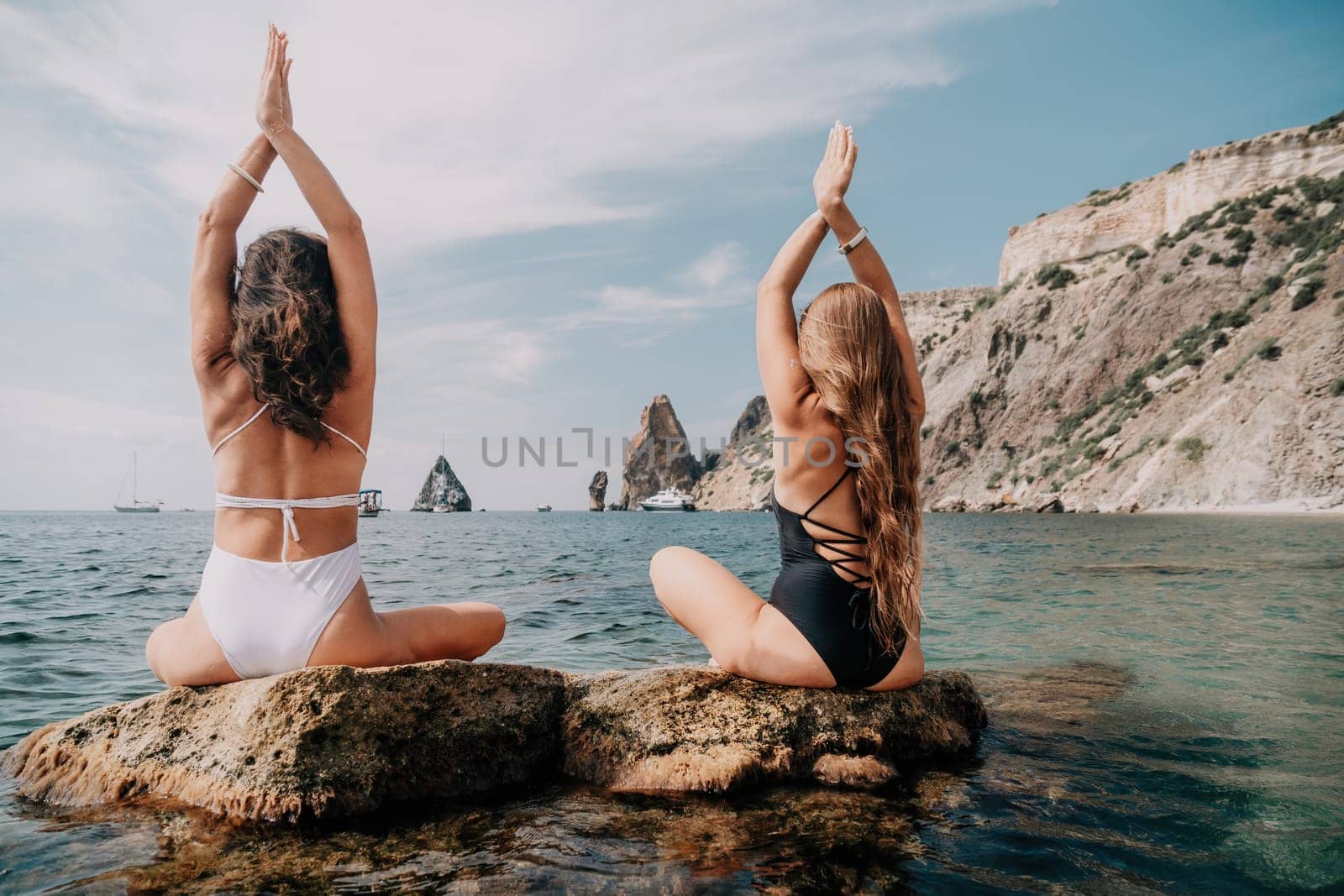 Woman sea yoga. Happy women meditating in yoga pose on the beach, ocean and rock mountains. Motivation and inspirational fit and exercising. Healthy lifestyle outdoors in nature, fitness concept. by panophotograph