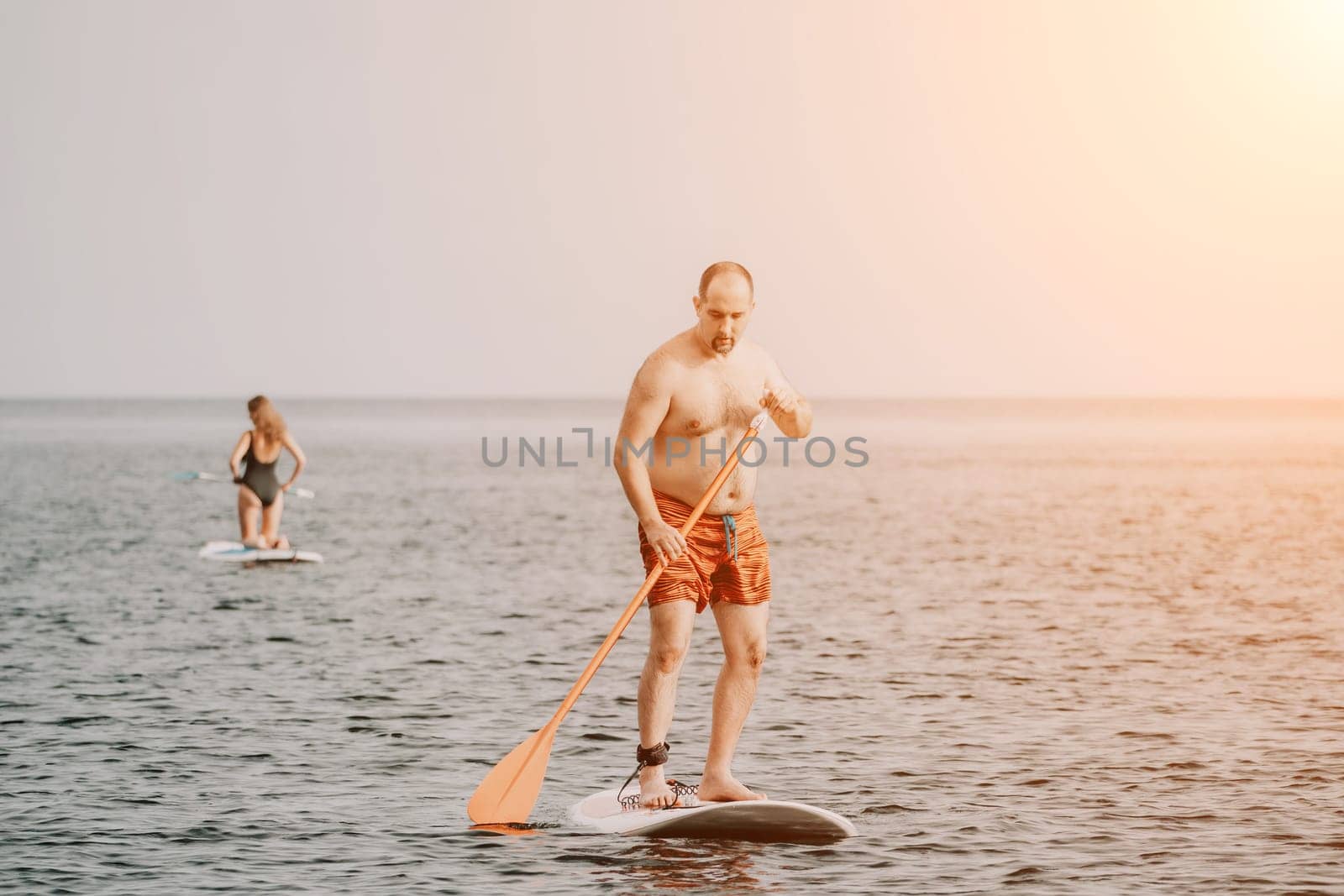 Active mature male paddler with his paddleboard and paddle on a sea at summer. Happy senior man stands with a SUP board. Stand up paddle boarding - outdor active recreation in nature. by panophotograph