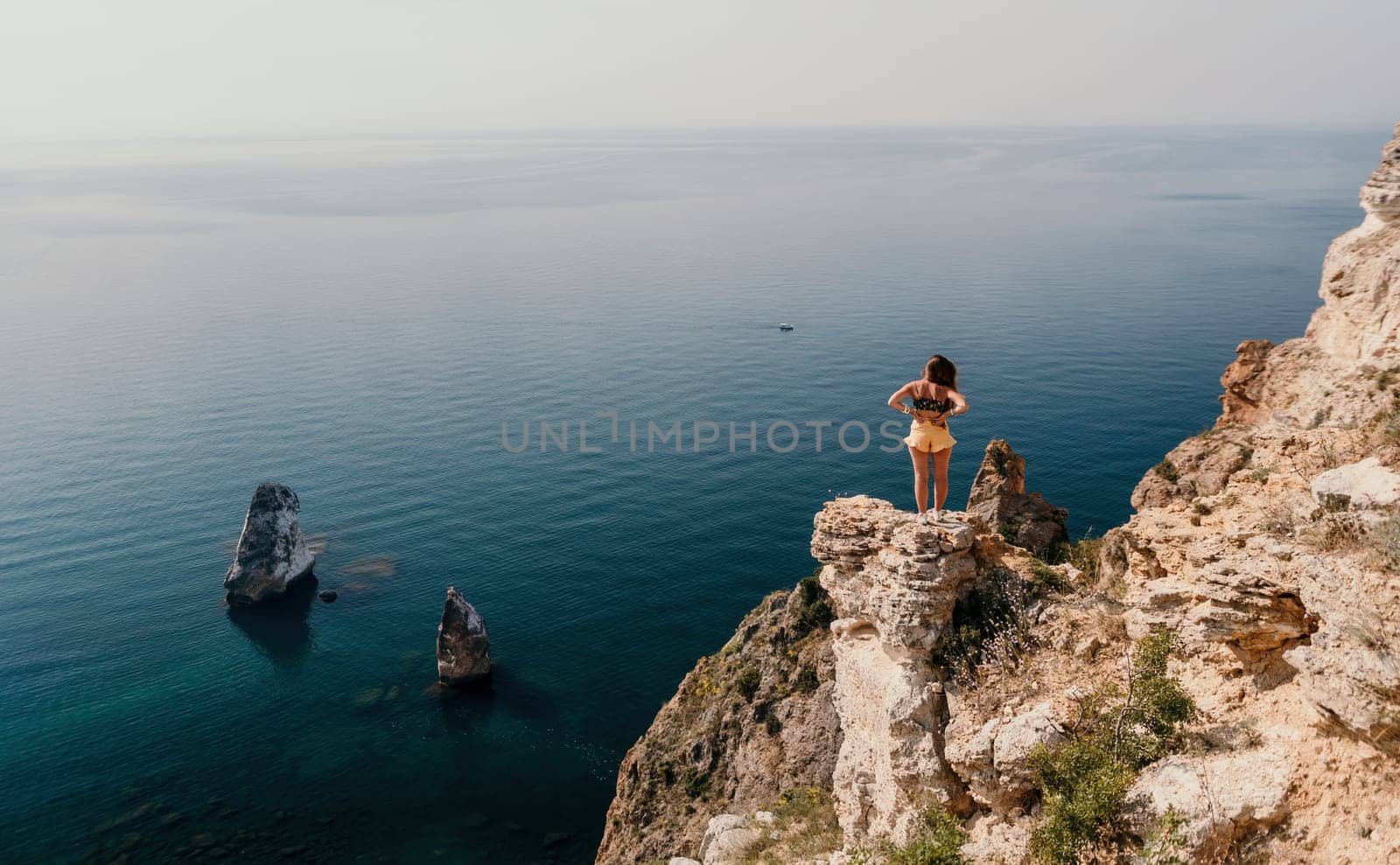 Woman travel sea. Happy tourist enjoy taking picture outdoors for memories. Woman traveler looks at the edge of the cliff on the sea bay of mountains, sharing travel adventure journey by panophotograph