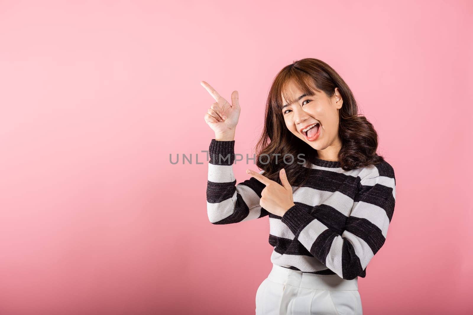 A smiling Asian woman points confidently by Sorapop