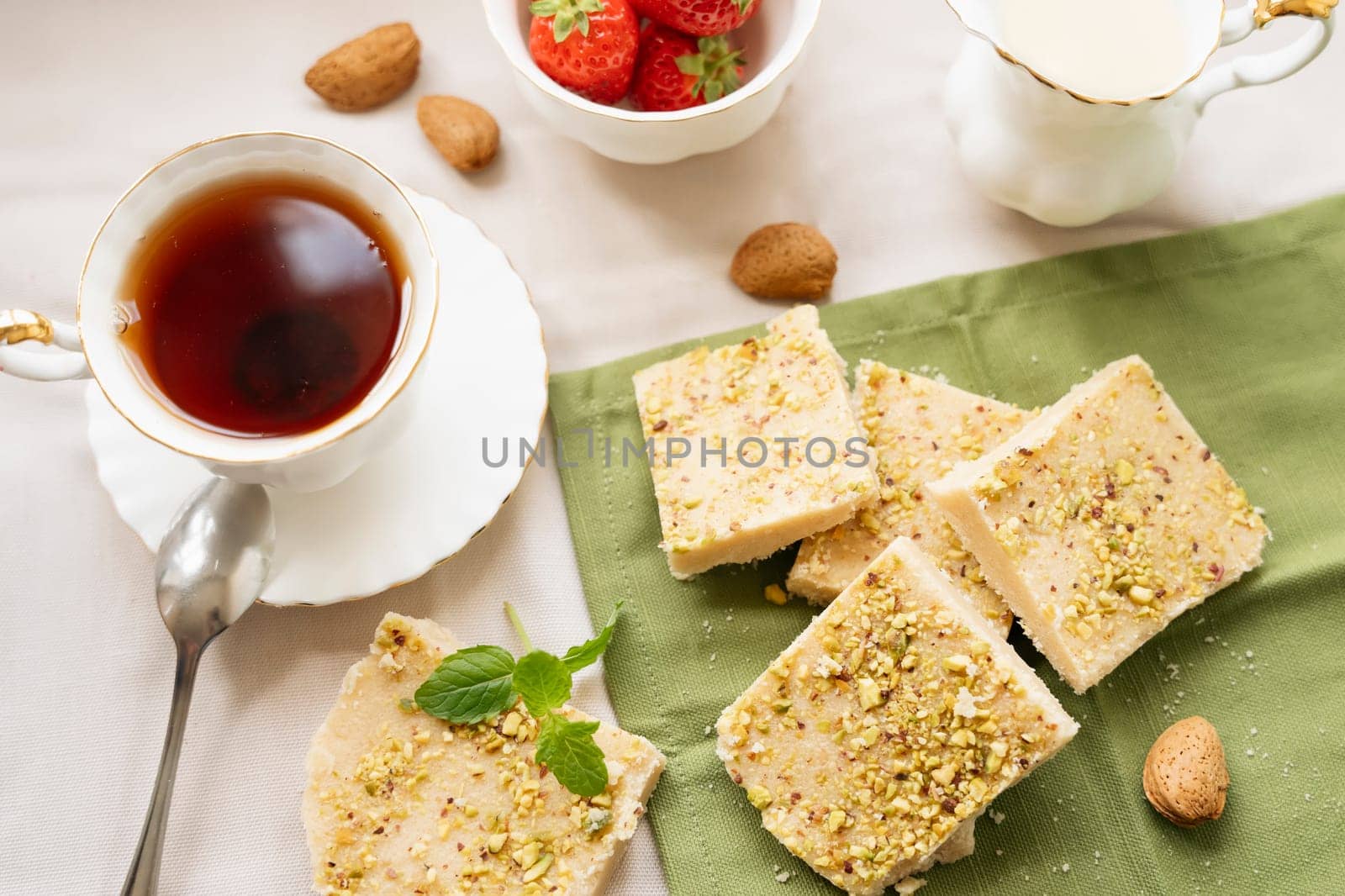 tea, milk, cakes, chocolate pieces, halva on the table by Iryna_Melnyk