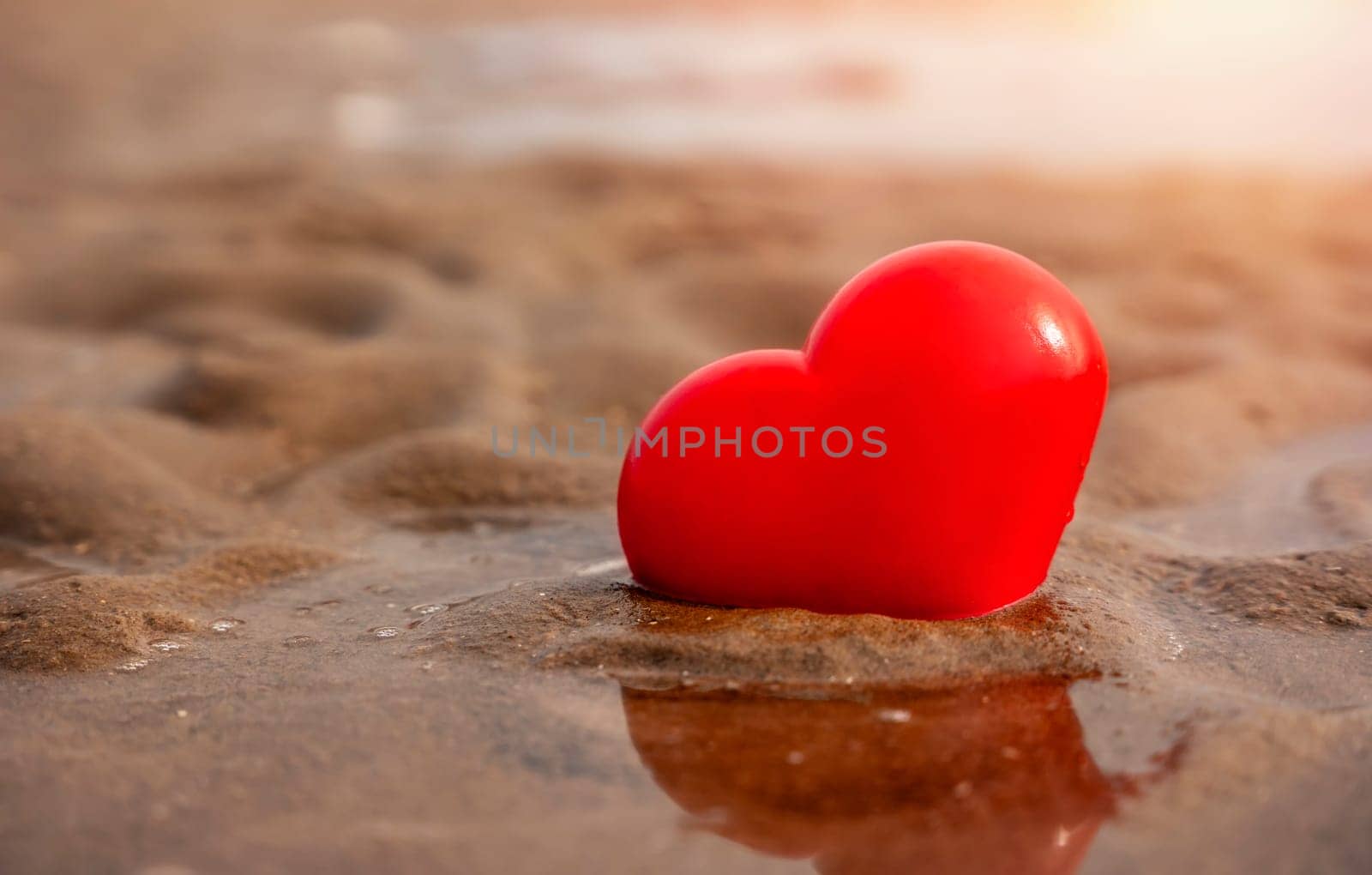Big red heart in sand at coast. Fall in love with holiday at seaside concept by Iryna_Melnyk