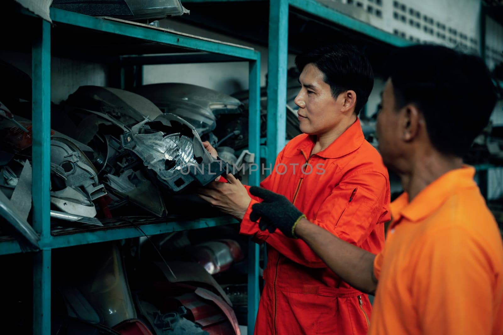 Mechanic worker inspect spare vehicle parts stored in inventory at automotive service. Reusing car components, optimizing resource and availability of spare part for repair and maintenance. Oxus