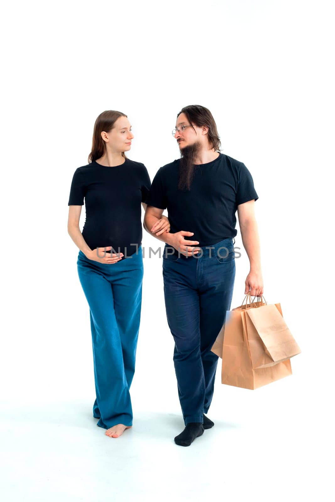 Portrait happy young pregnant woman and her husband with shopping bags and touching her big belly isolated on white background. Pregnancy shopping concept happy young family with shopping bags