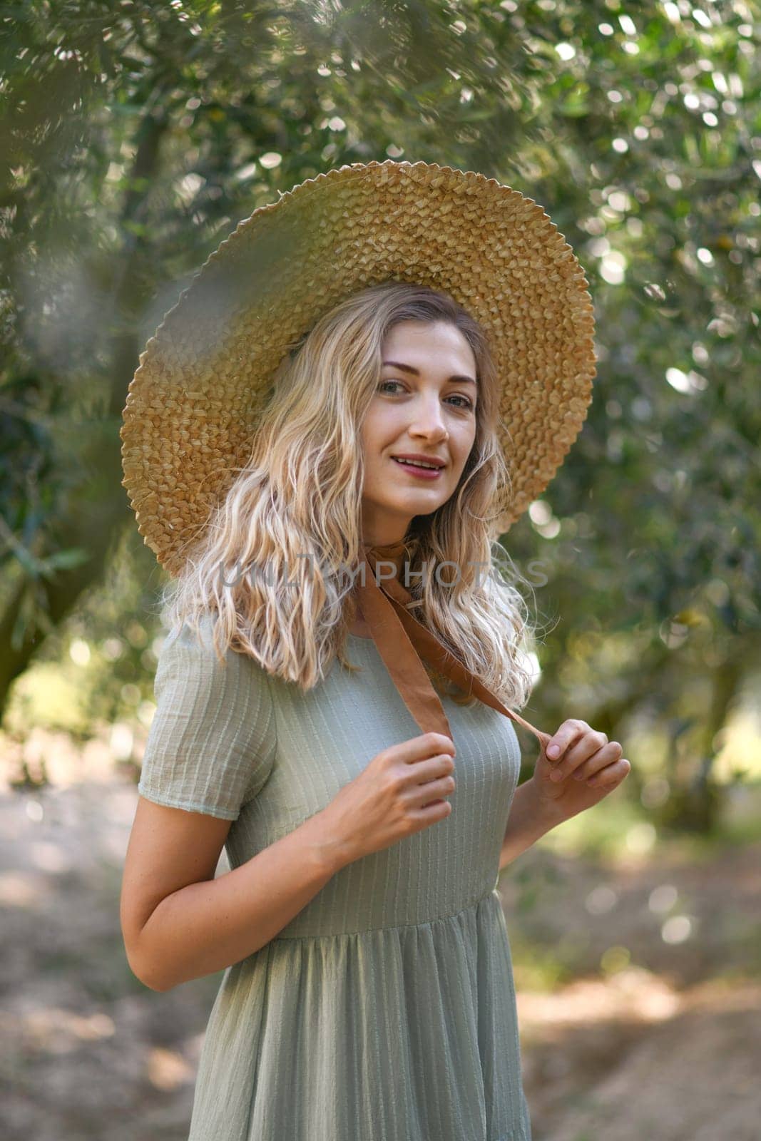 Blonde woman in a straw hat near olive tree in garden in Provence, France