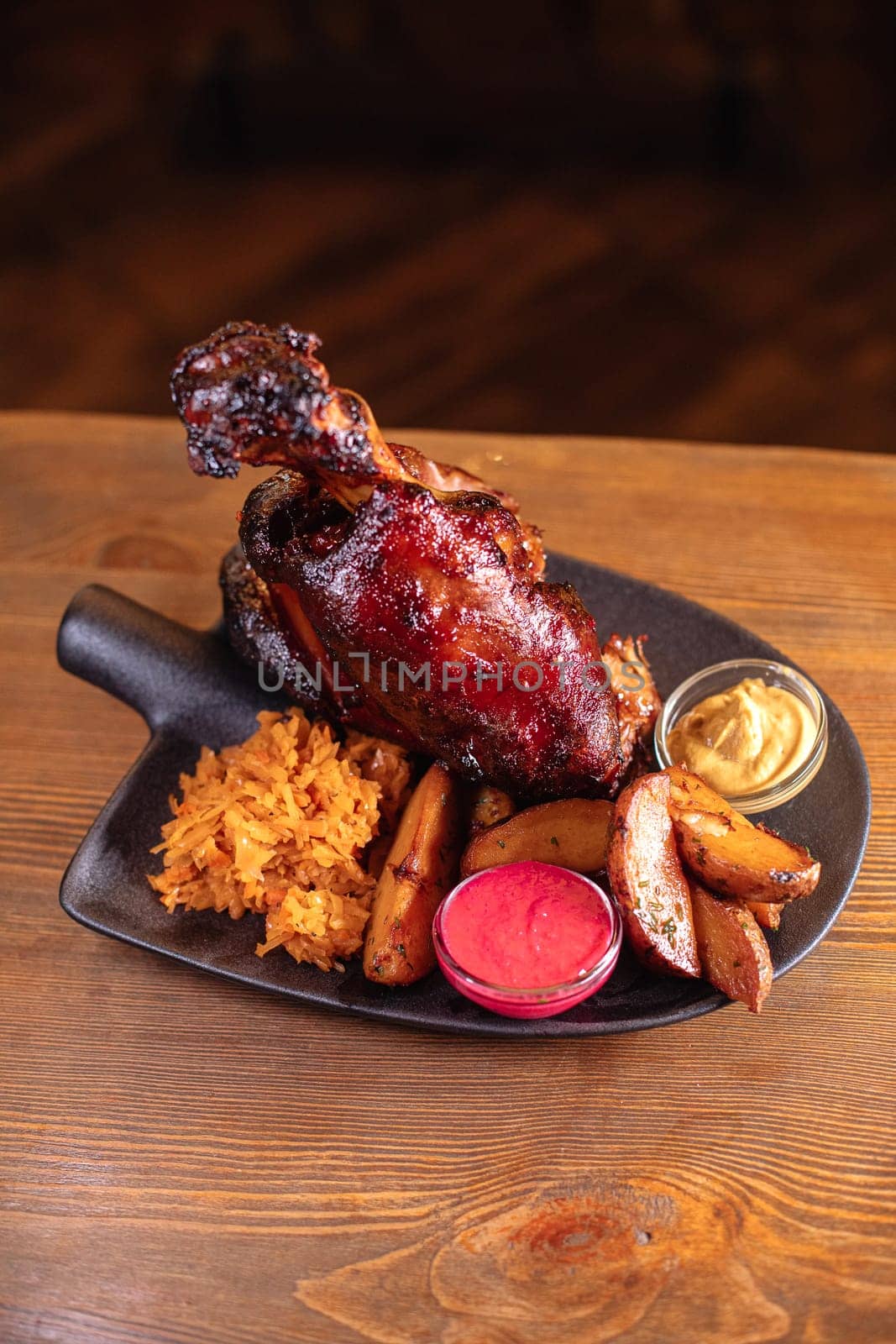 Juicy baked pork knuckle served beautifully on a plate with a shovel. A delicious photo for a menu, culinary website, or an advertisement for catering establishments