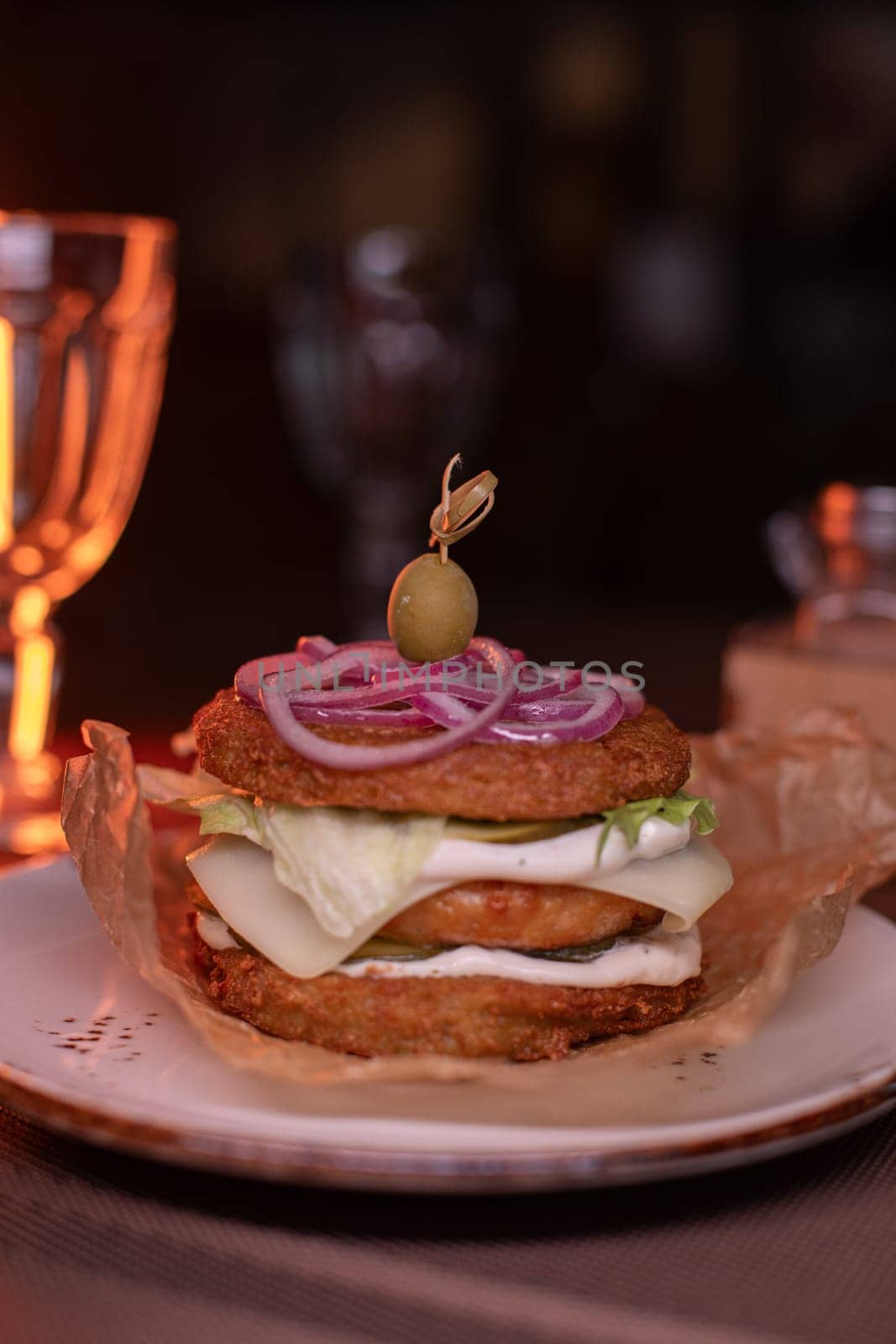 Juicy burger made from draniki and meat patties, lettuce, onion on top and olive. A delicious photo for a menu, culinary website, or an advertisement for catering establishments.