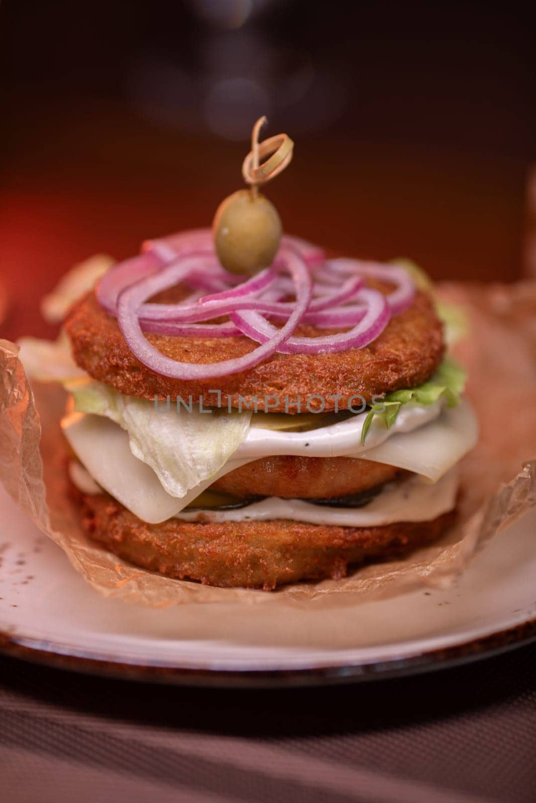 Juicy burger made from draniki and meat patties, lettuce, onion on top and olive. A delicious photo for a menu, culinary website, or an advertisement for catering establishments.