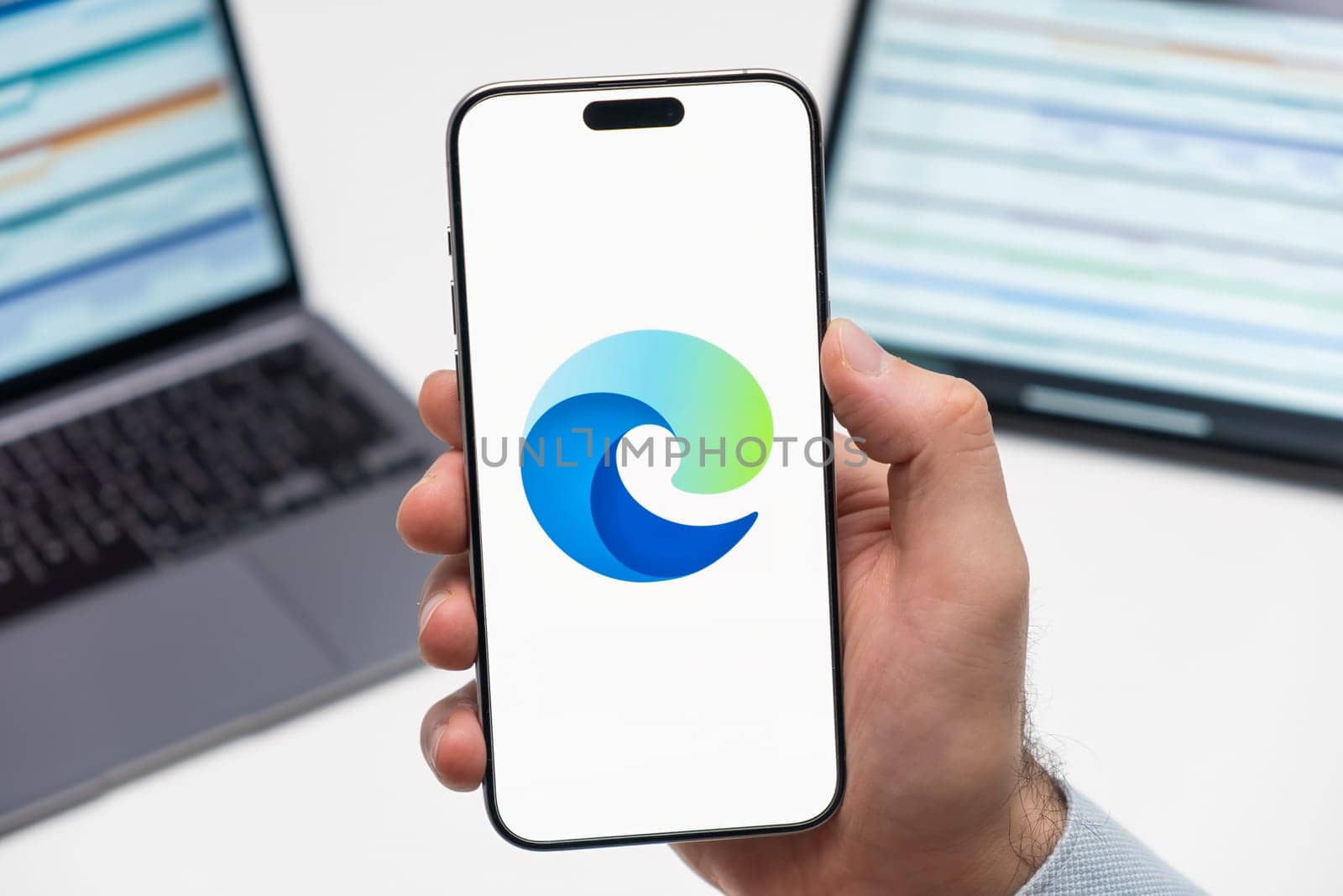 PRAGUE, CZECH REPUBLIC - JANUARY 21 2024: Microsoft Edge logo on the screen of smartphone in mans hand on the workplace background.