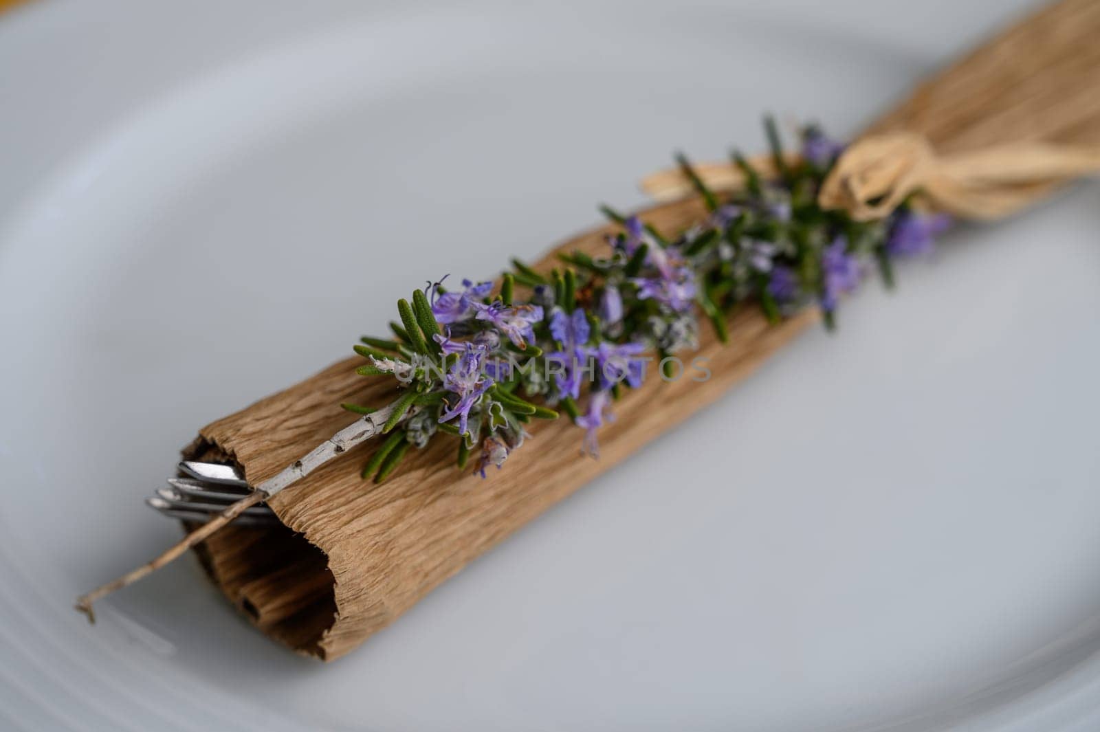 Fresh rosemary wrapped in natural materials adds a touch of nature to a summer dining experience.