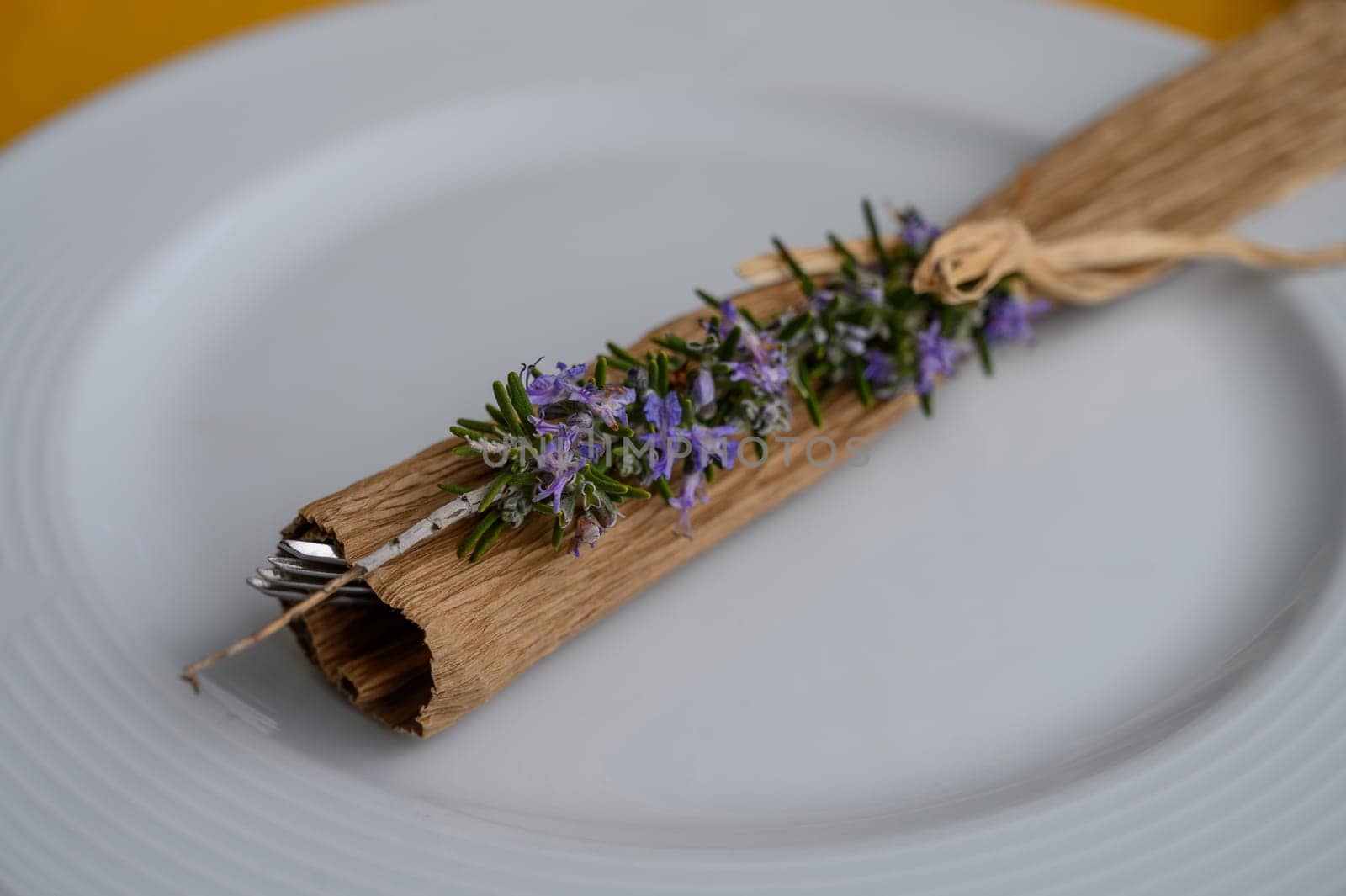Delicate rosemary and lavender adorn a handmade napkin holder on a beautifully set table for an intimate meal.