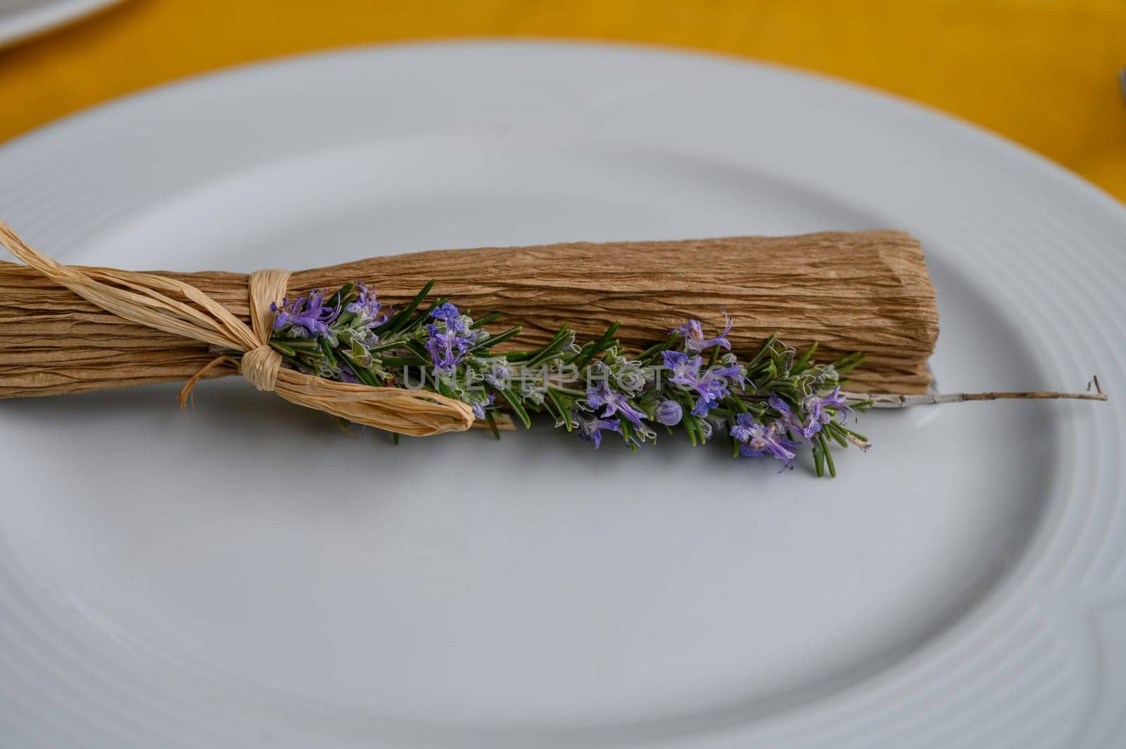 Delicate rosemary and lavender creatively arranged with natural fibers on a white plate, enhancing rustic charm.