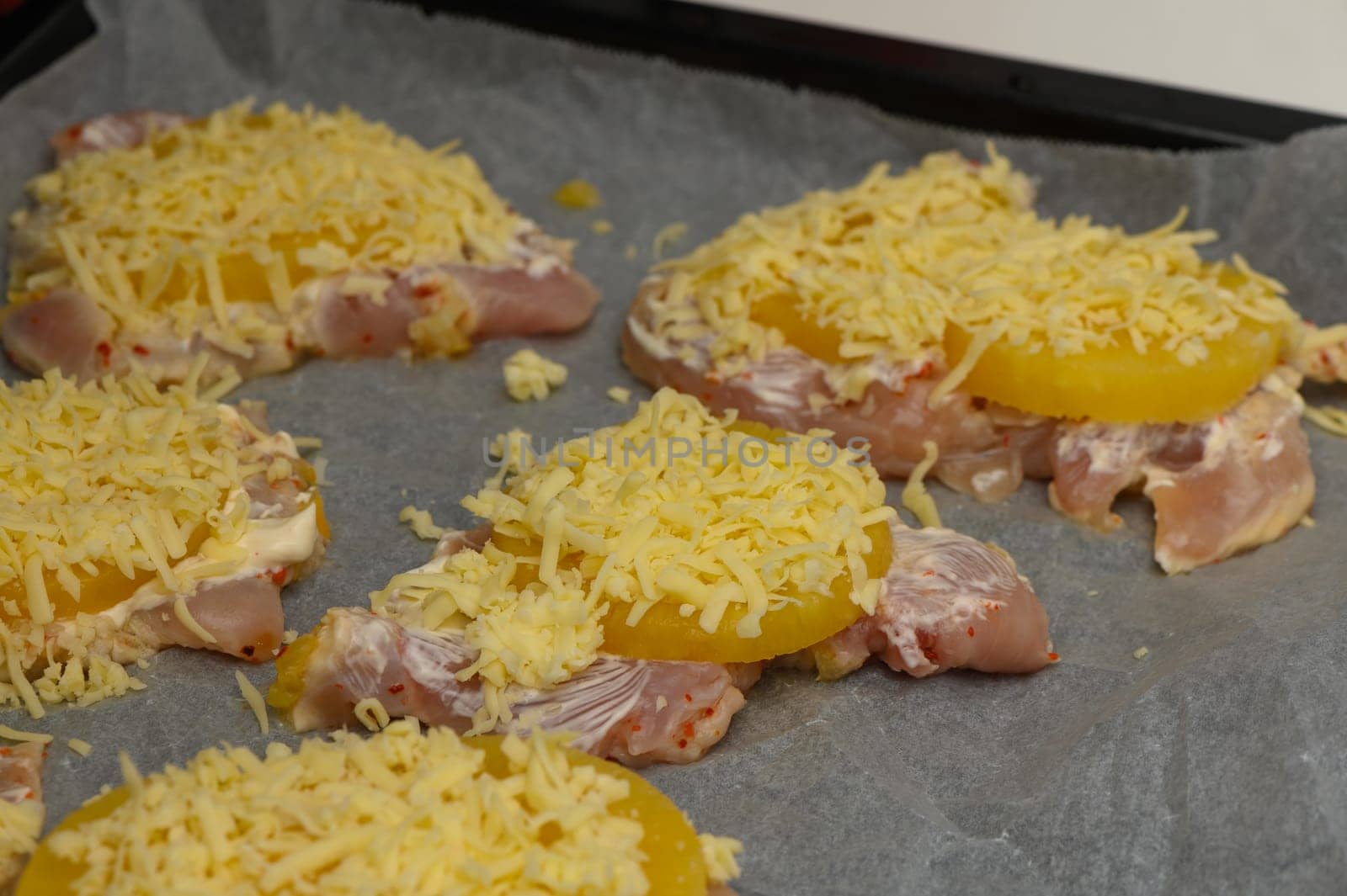 Chicken pieces layered with pineapple slices and a generous topping of shredded cheese await the baking process.