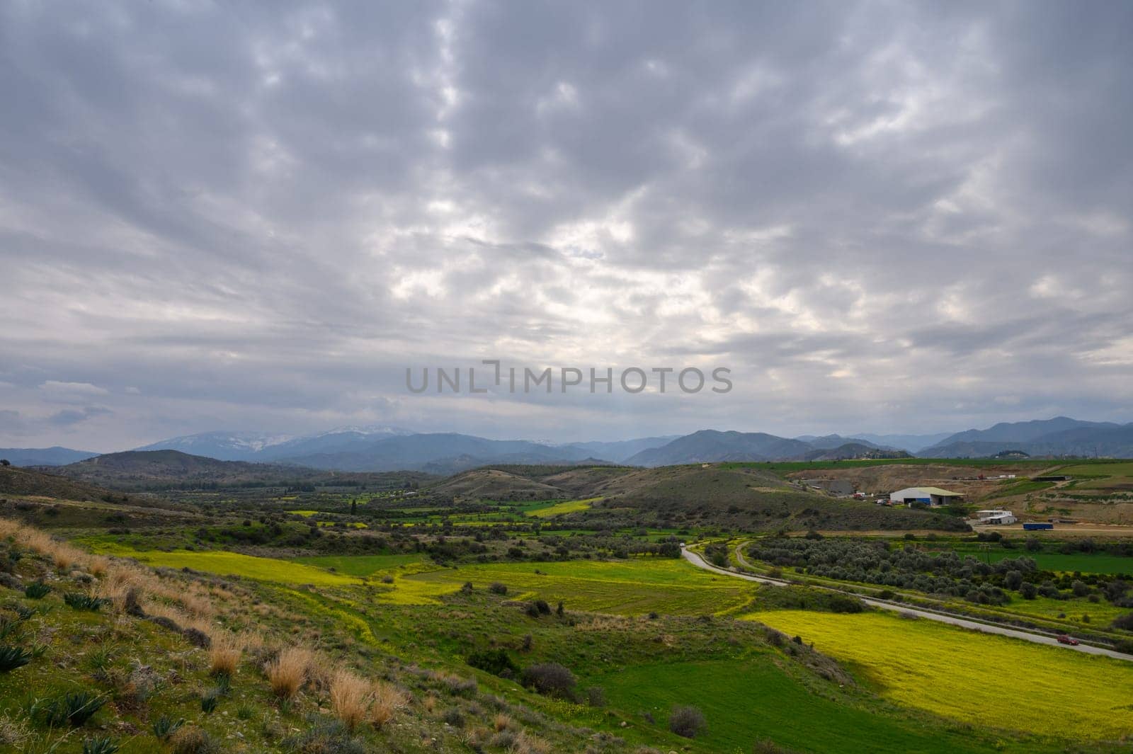 Rolling green hills intersperse with golden fields, embraced by an overcast sky, inviting a peaceful outdoor experience.