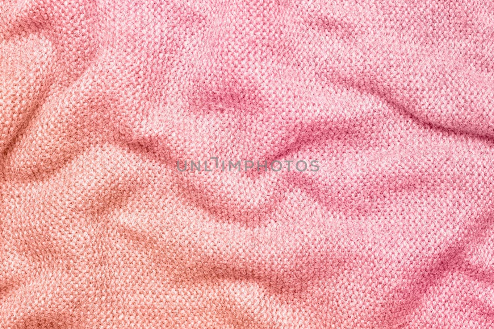 A soft and textured gradient pink knitted fabric with gentle waves and folds, creating a cozy and warm appearance. Ideal for textile backgrounds, fashion, or home decor themes.