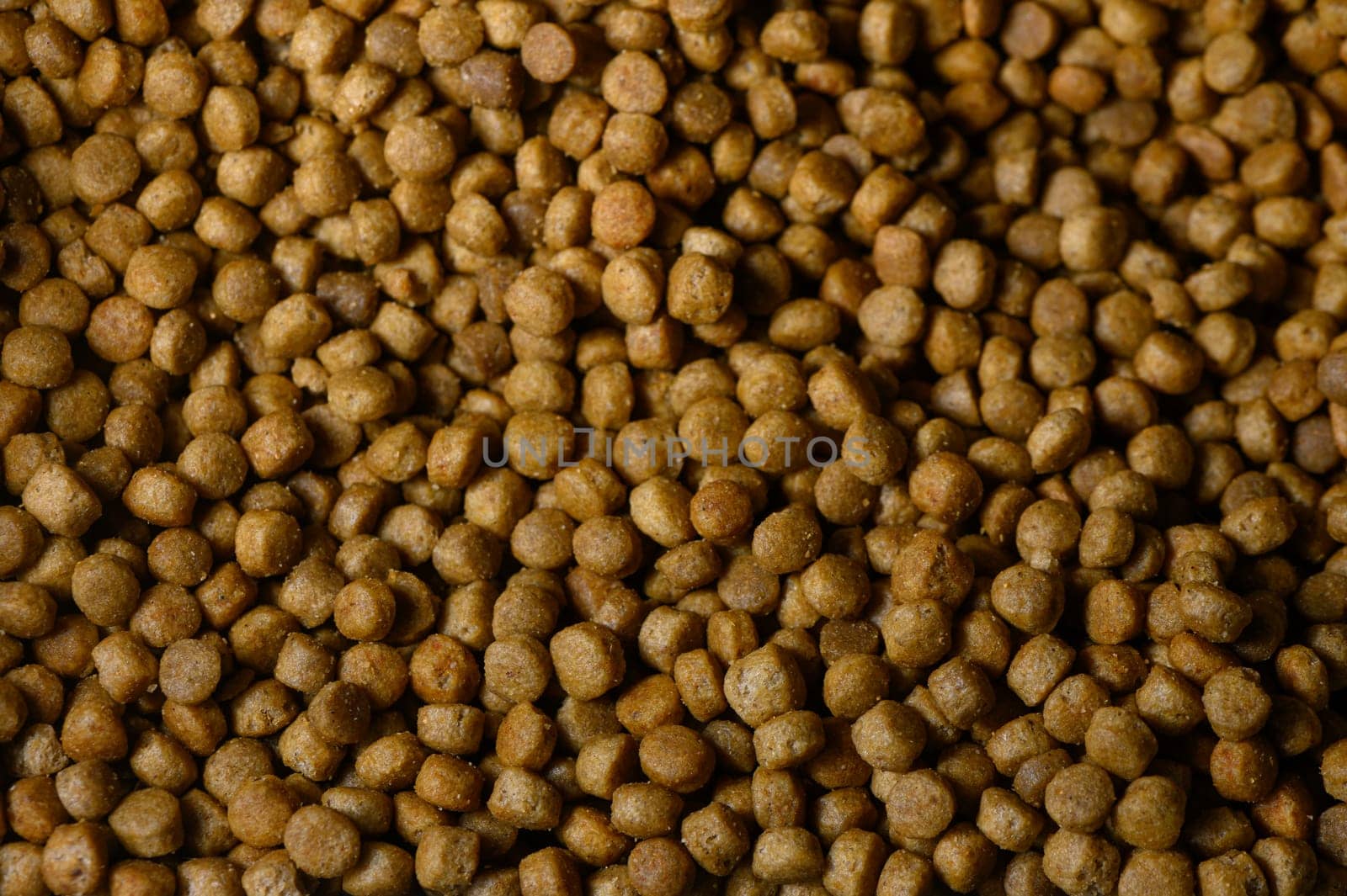 Brown pet food pellets are tightly packed together, revealing their unique shapes and textures in natural light.