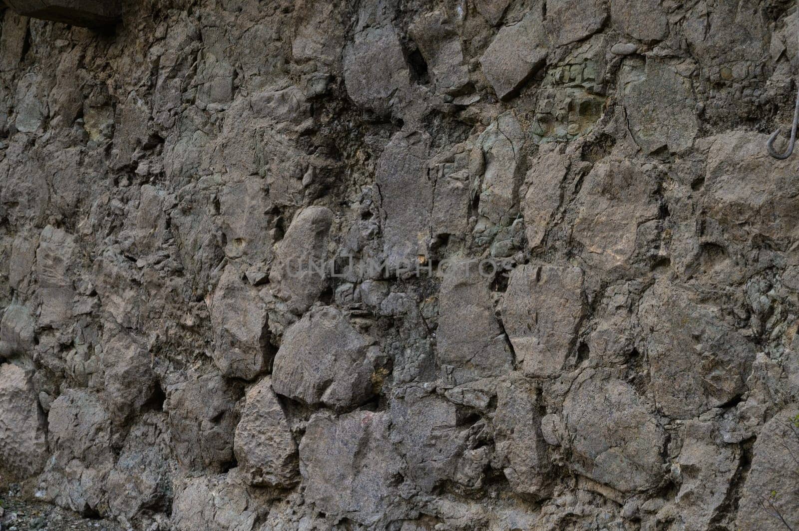 Ancient stones form a rugged wall, showing texture and history under soft light in a serene environment.
