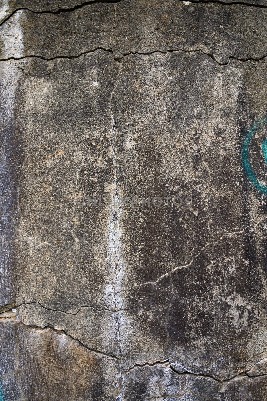 Texture of a cracked stone wall covered with vibrant graffiti, reflecting artistic expression and urban decay.