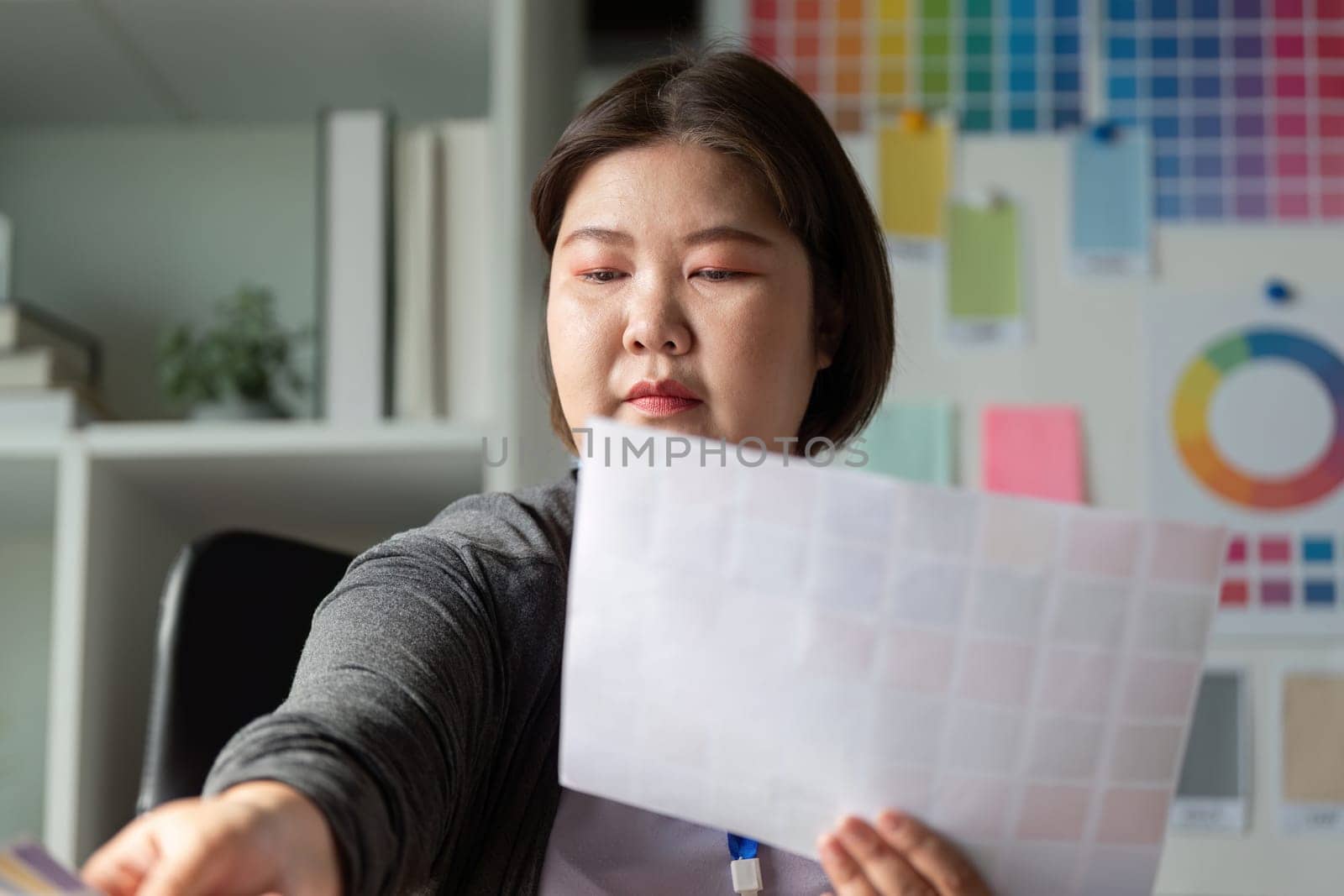A diverse graphic designer carefully selecting color swatches while focusing on a project in a bright creative environment.