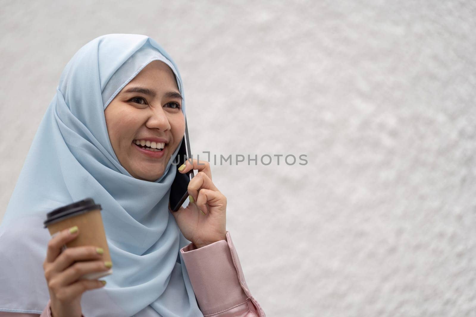 A cheerful Muslim businesswoman engages in a phone conversation, showcasing professionalism and cultural diversity in a contemporary setting.