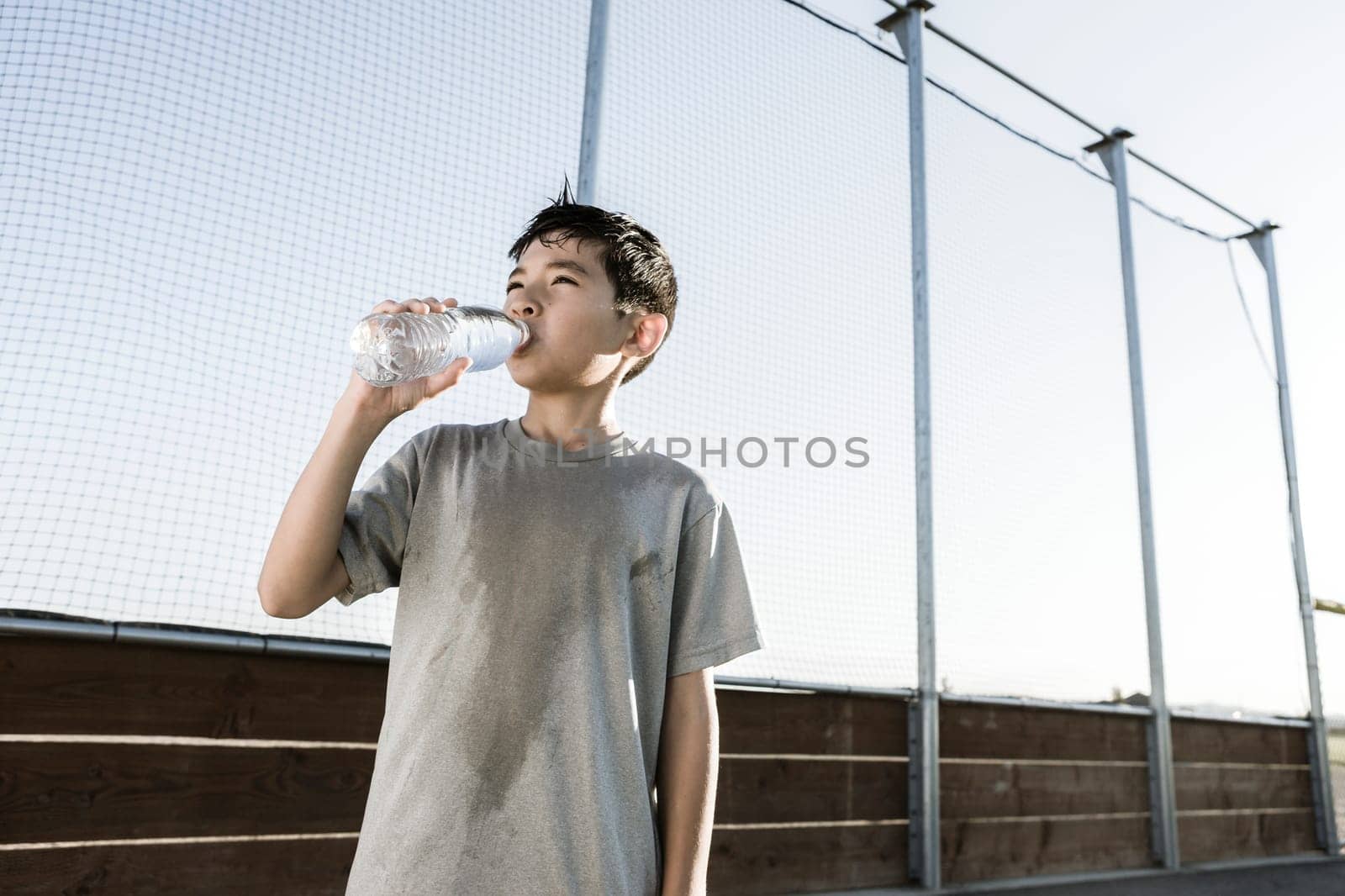A young boy drinks water after a hard day of practice.